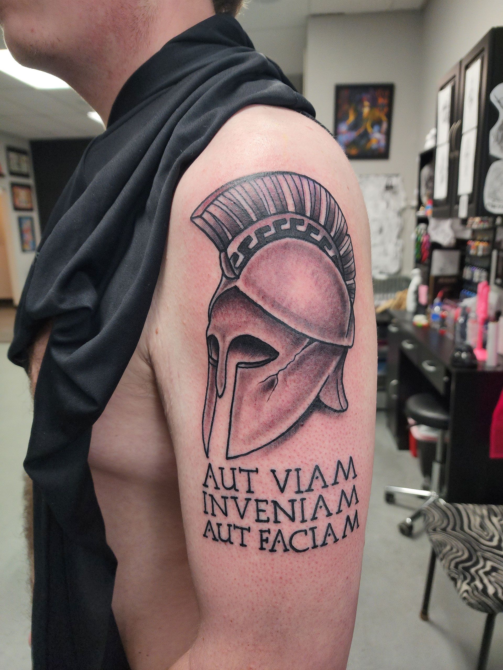 A man has a tattoo of a spartan helmet on his arm