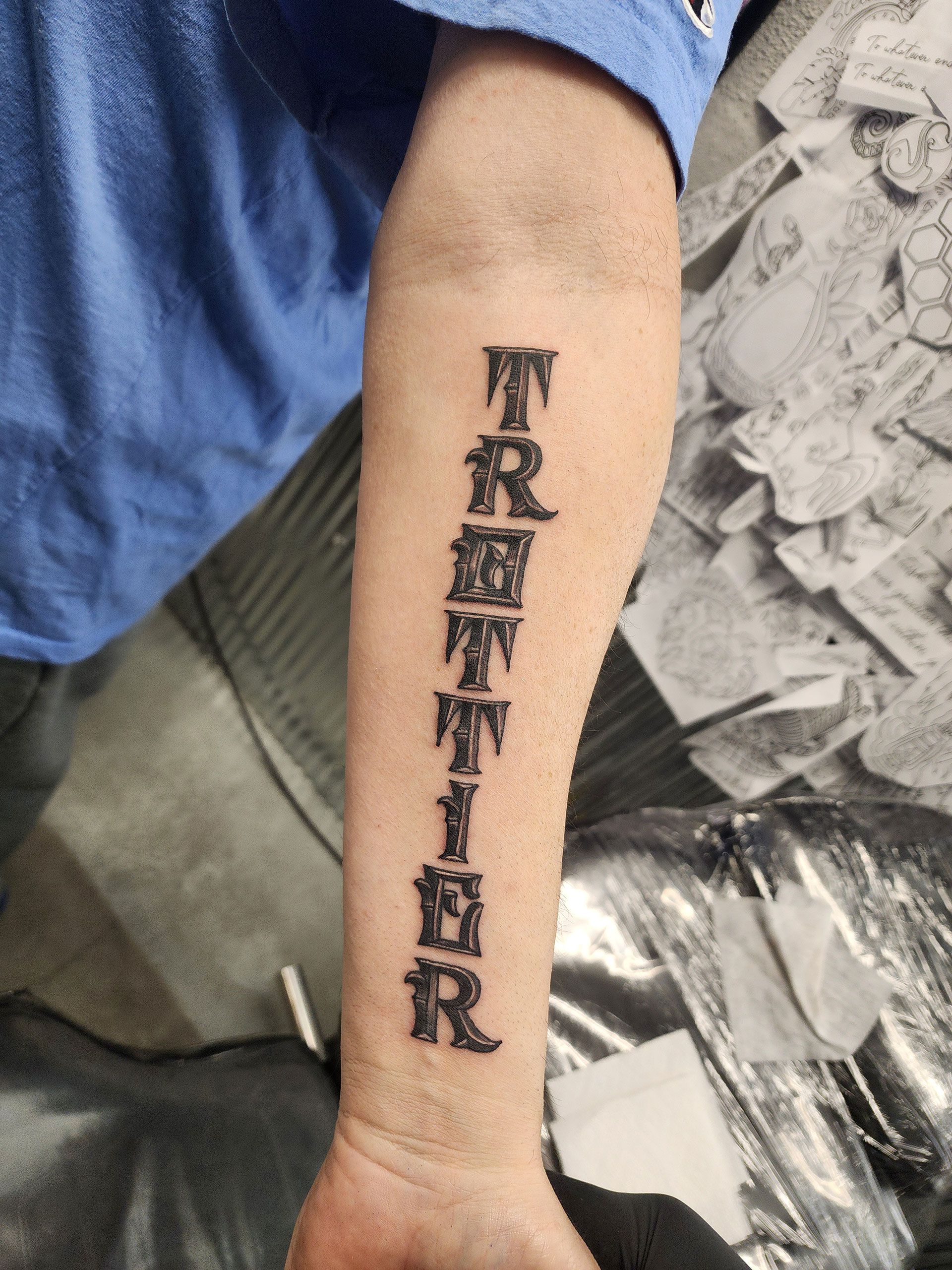 A man has a tattoo on his forearm that says trottier