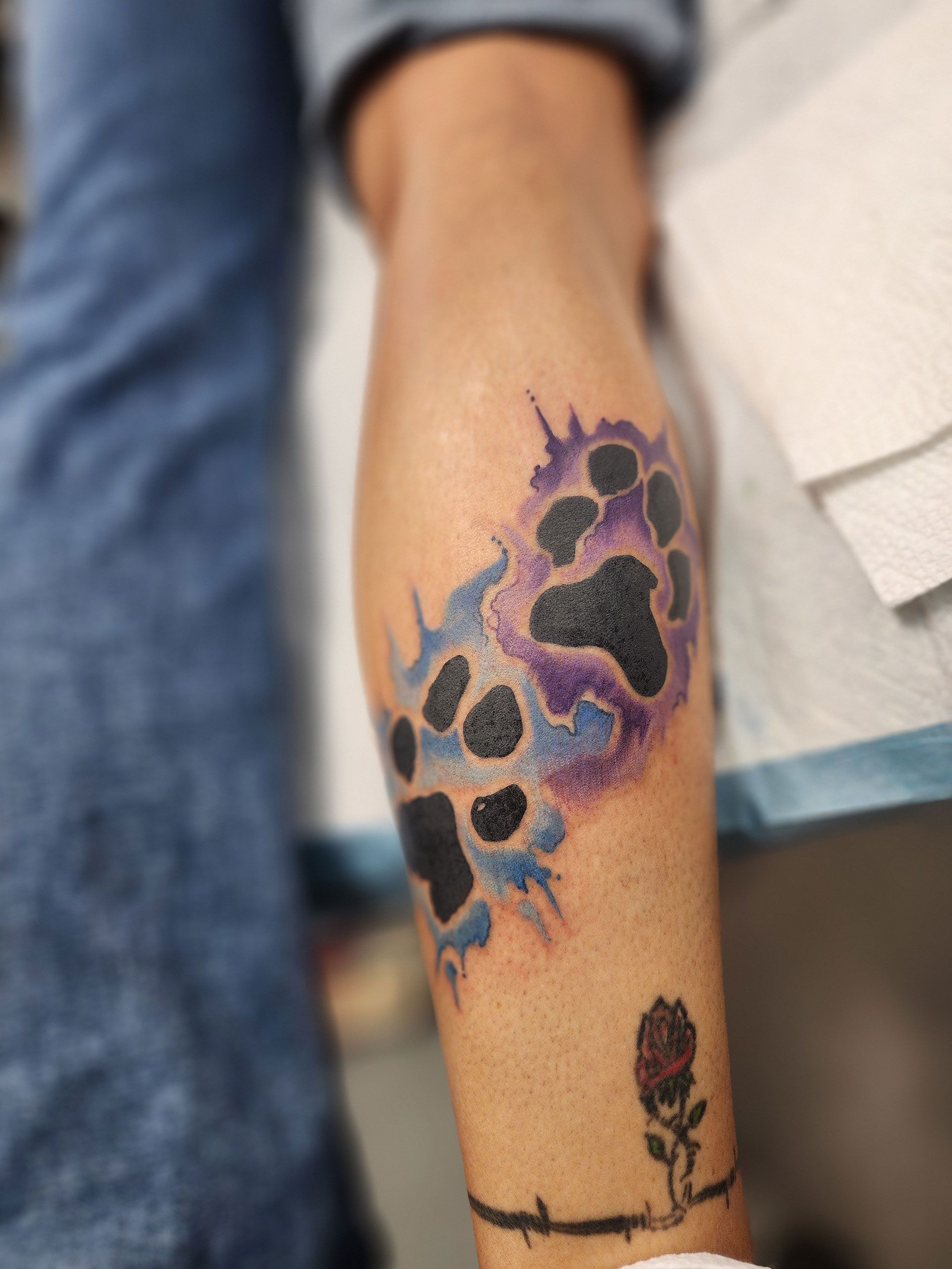 A person has a paw print tattoo on their leg