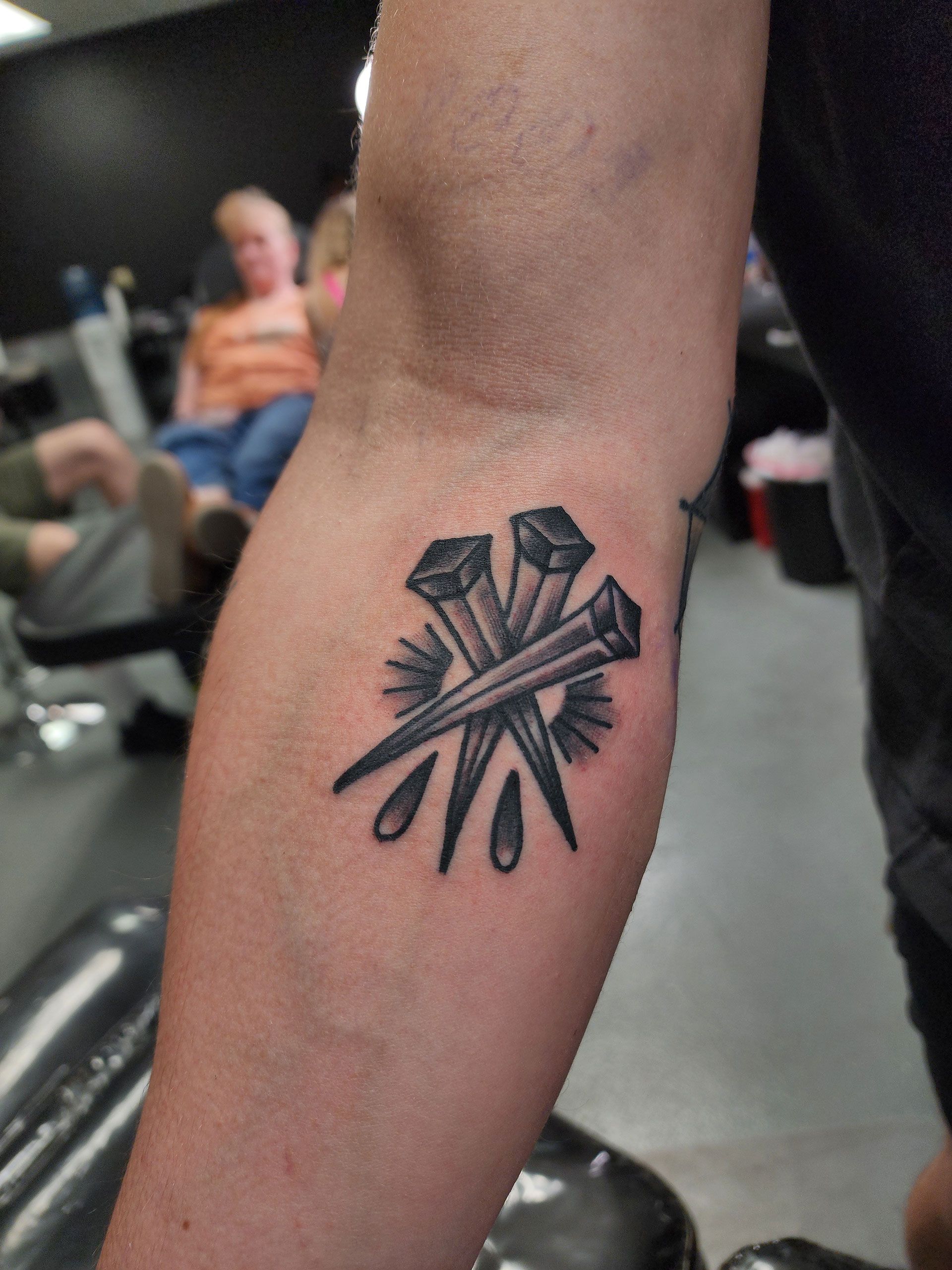 A tattoo of nails on a person's arm