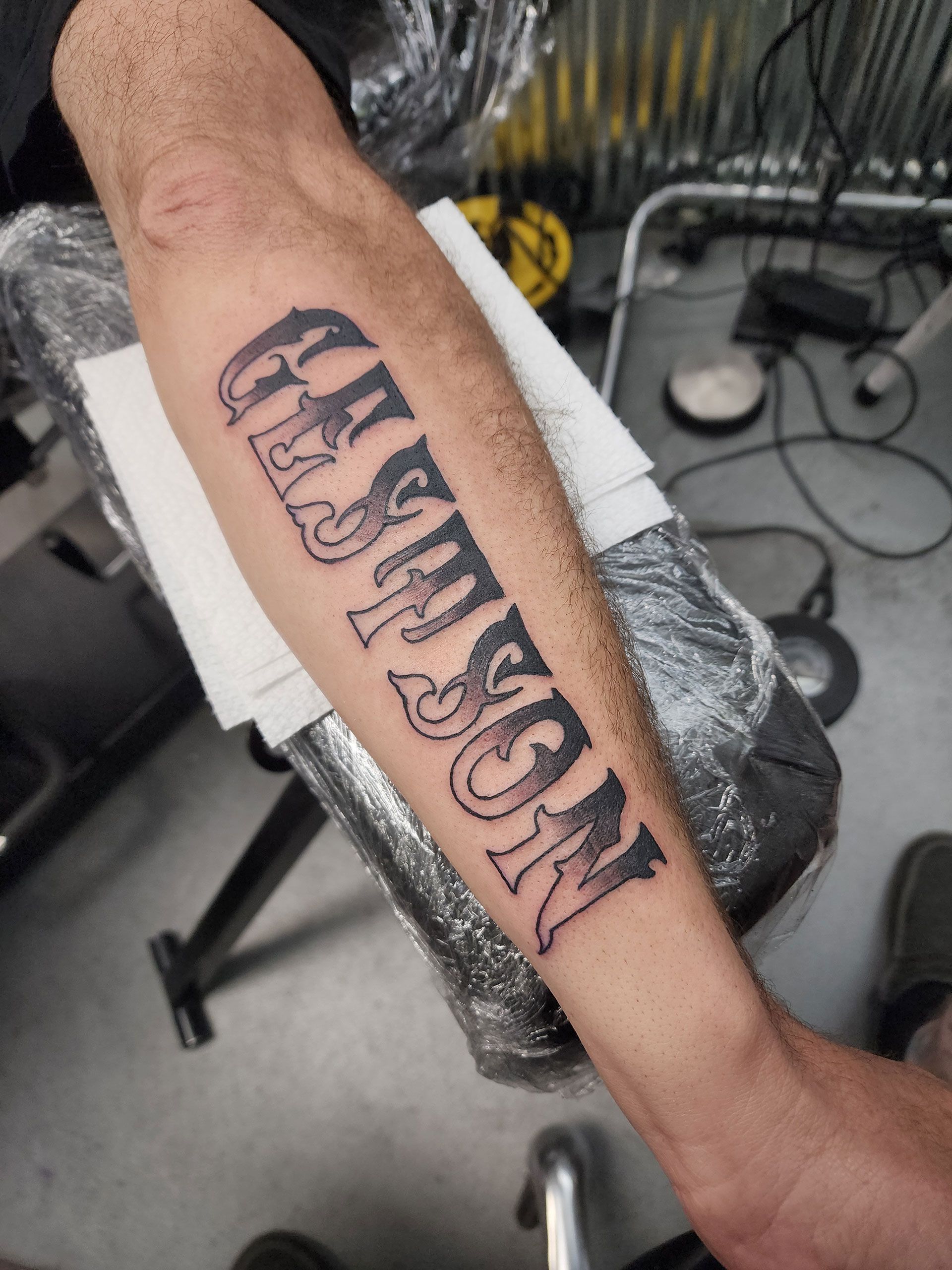 A man has a tattoo of the name Gestson on his forearm