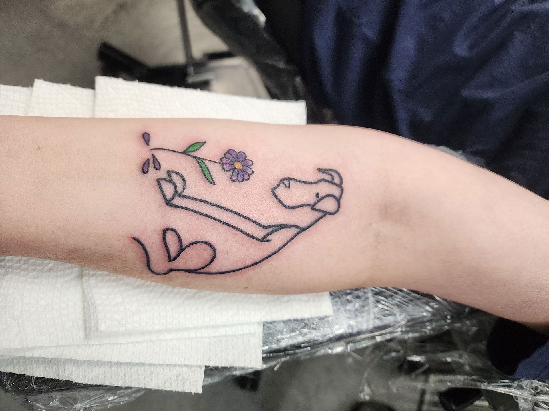 A tattoo dog silhouette and a flower on a person's arm