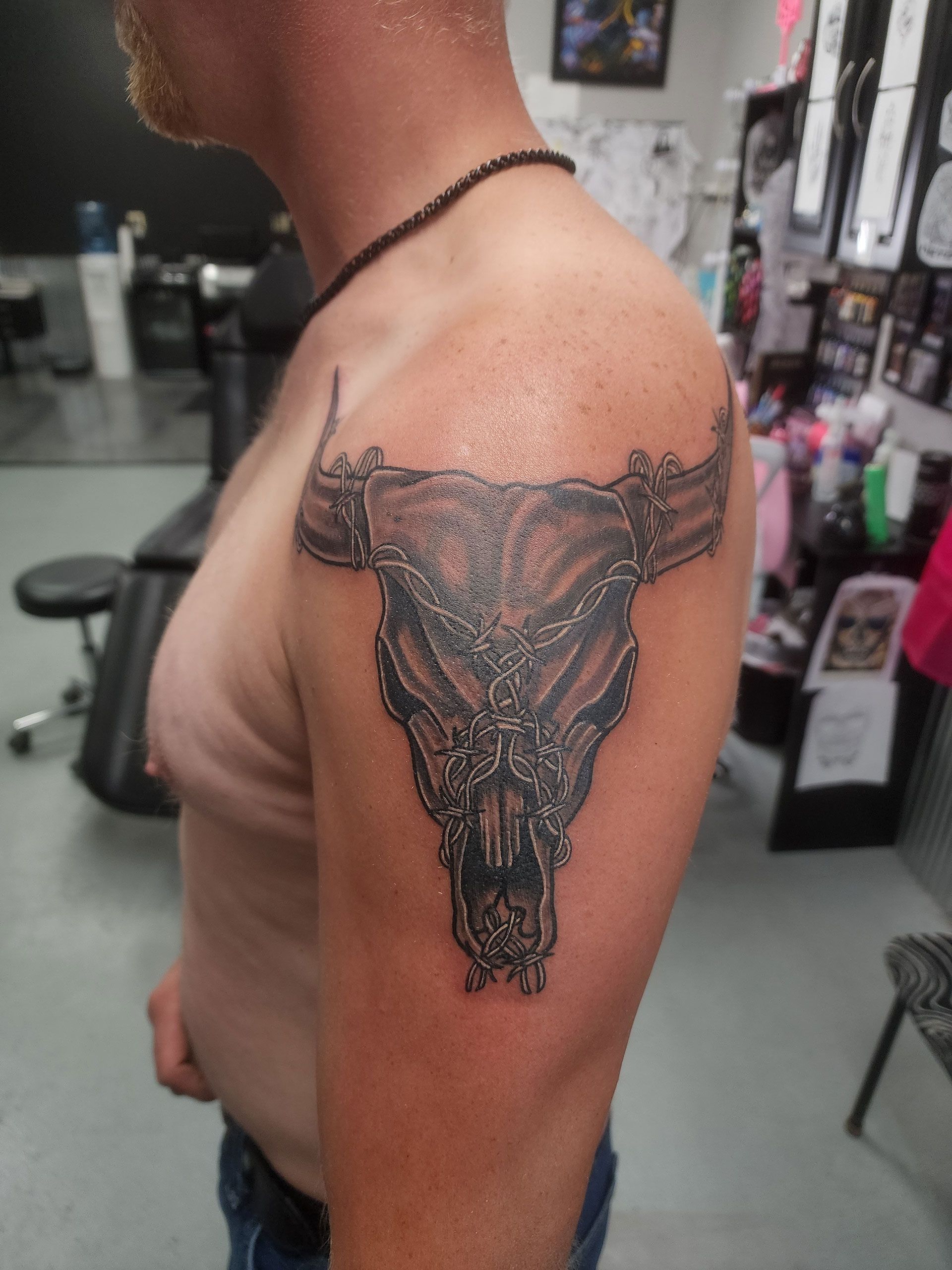A man has a tattoo of a bull skull on his arm
