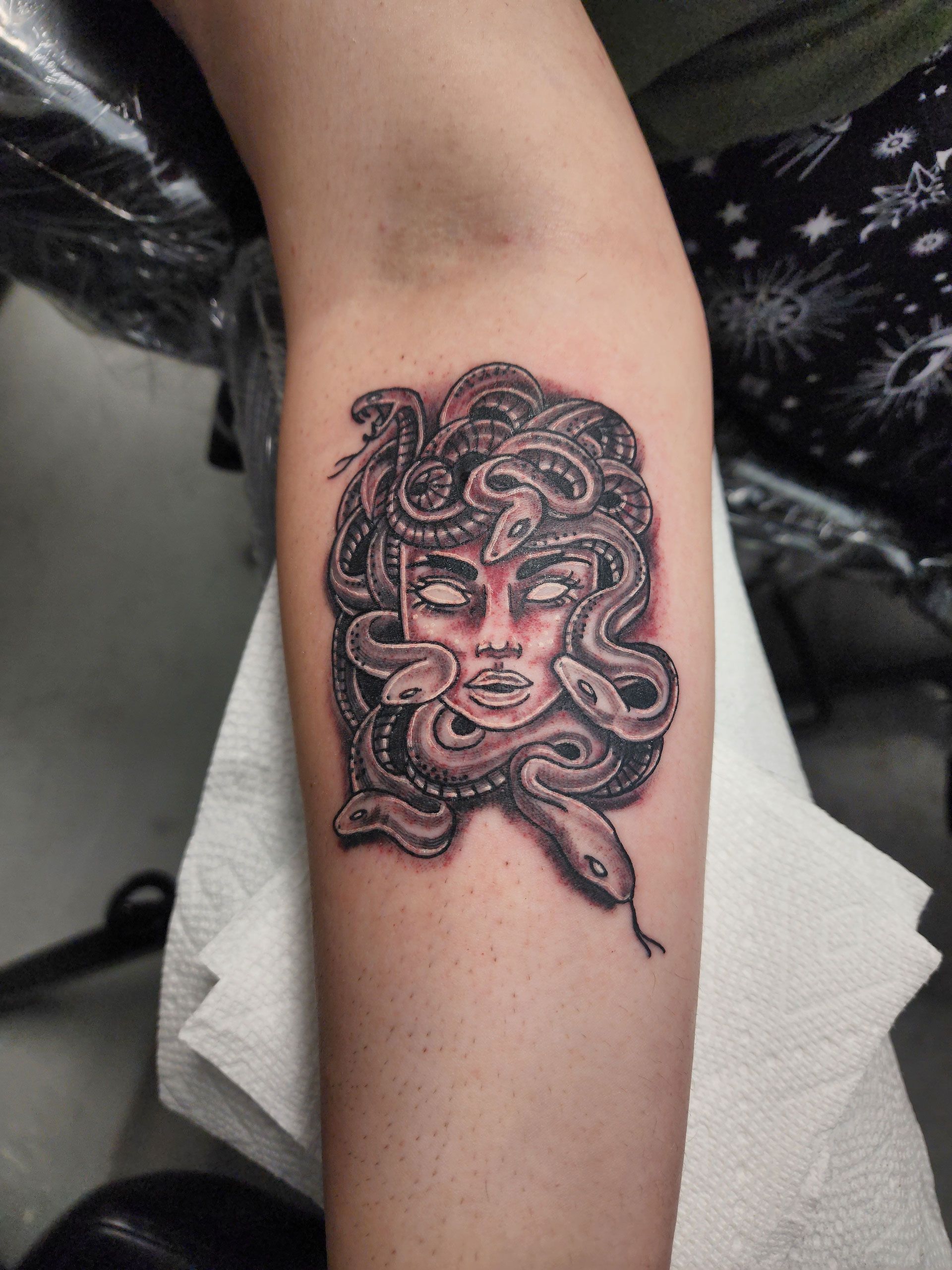 A person has a medusa tattoo on their forearm