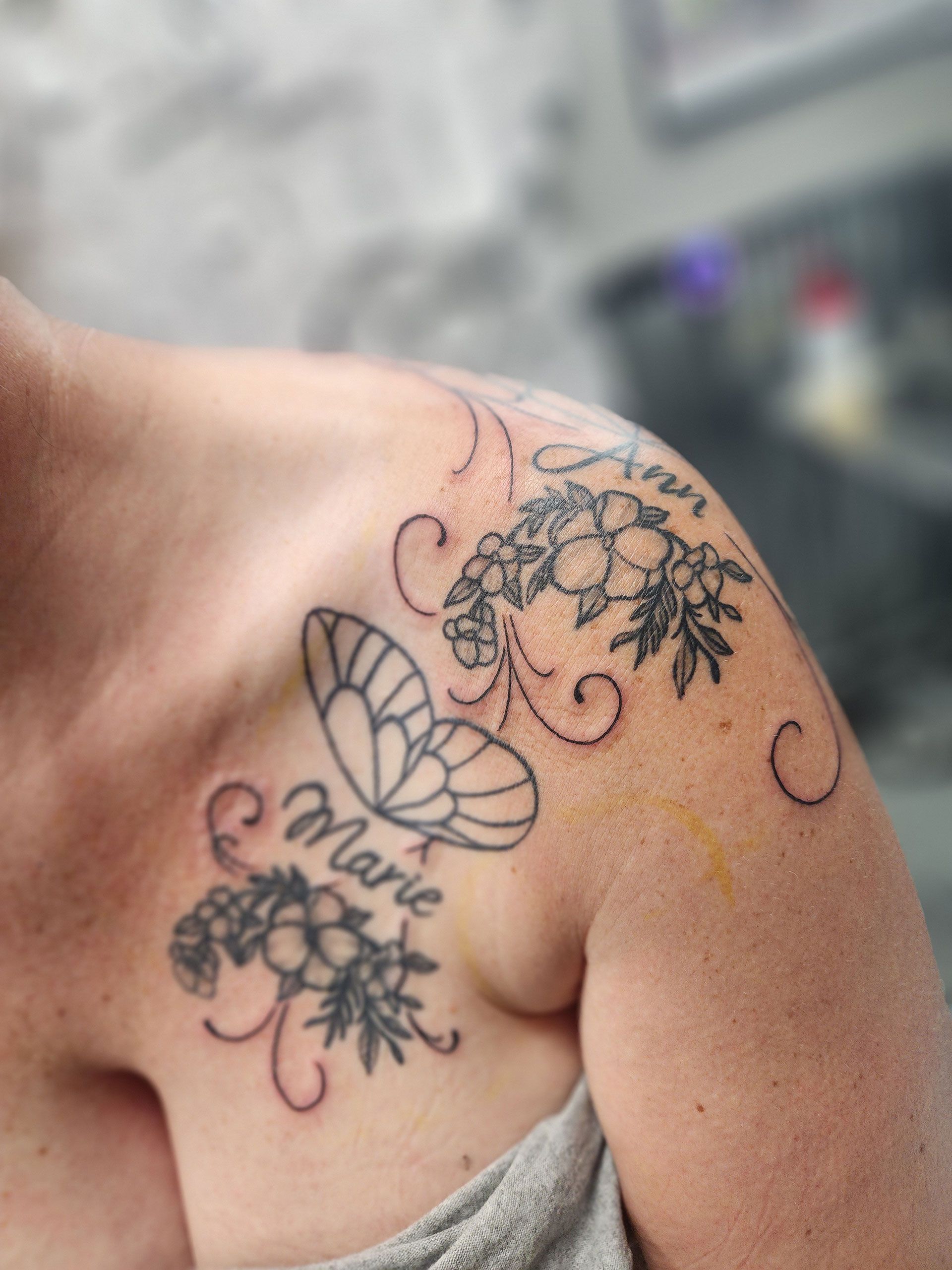 A woman has a tattoo on her shoulder that says marie