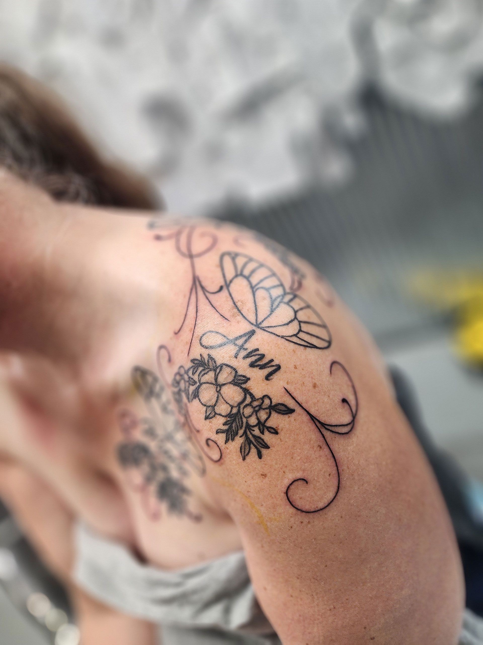 A woman has a tattoo on her shoulder and chest