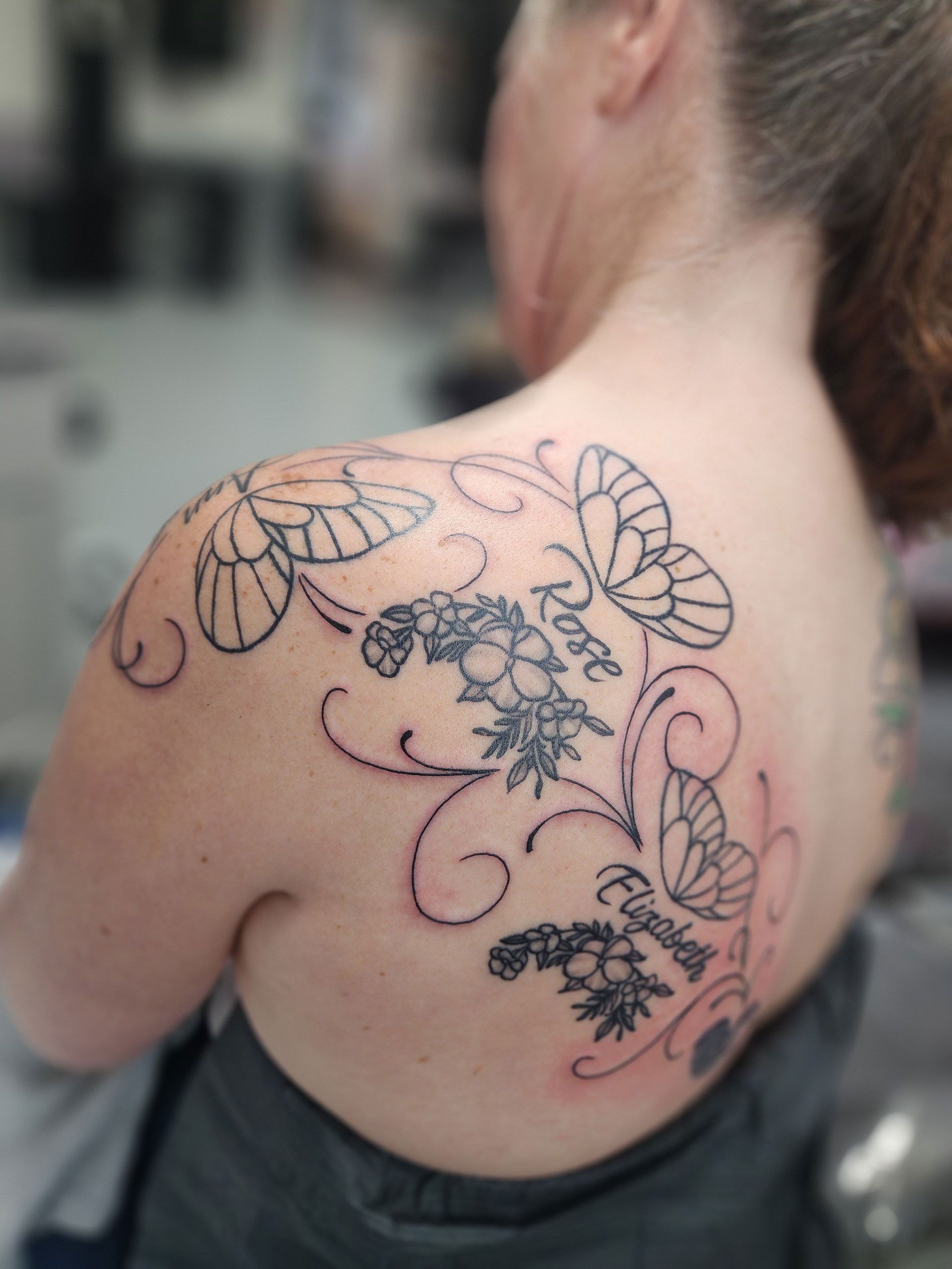 A woman has a tattoo of butterflies and flowers on her back