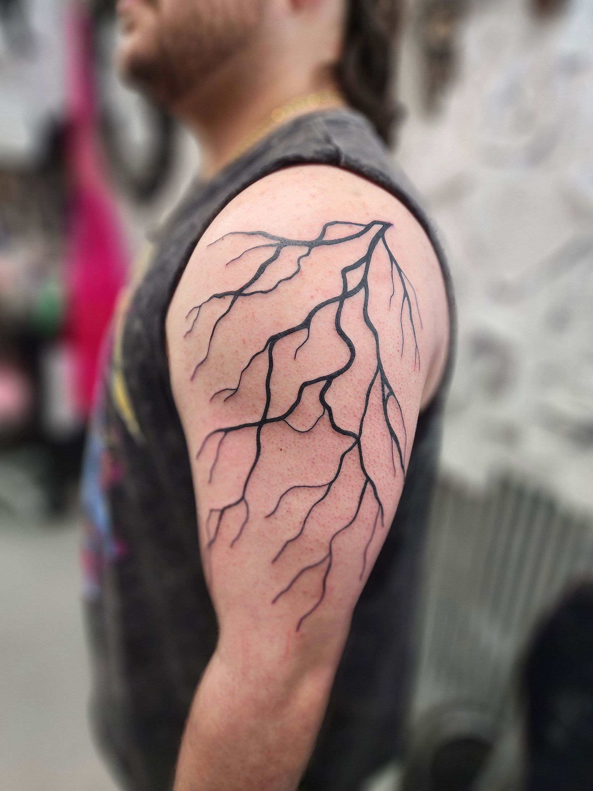A man has a lightning bolt tattoo on his arm