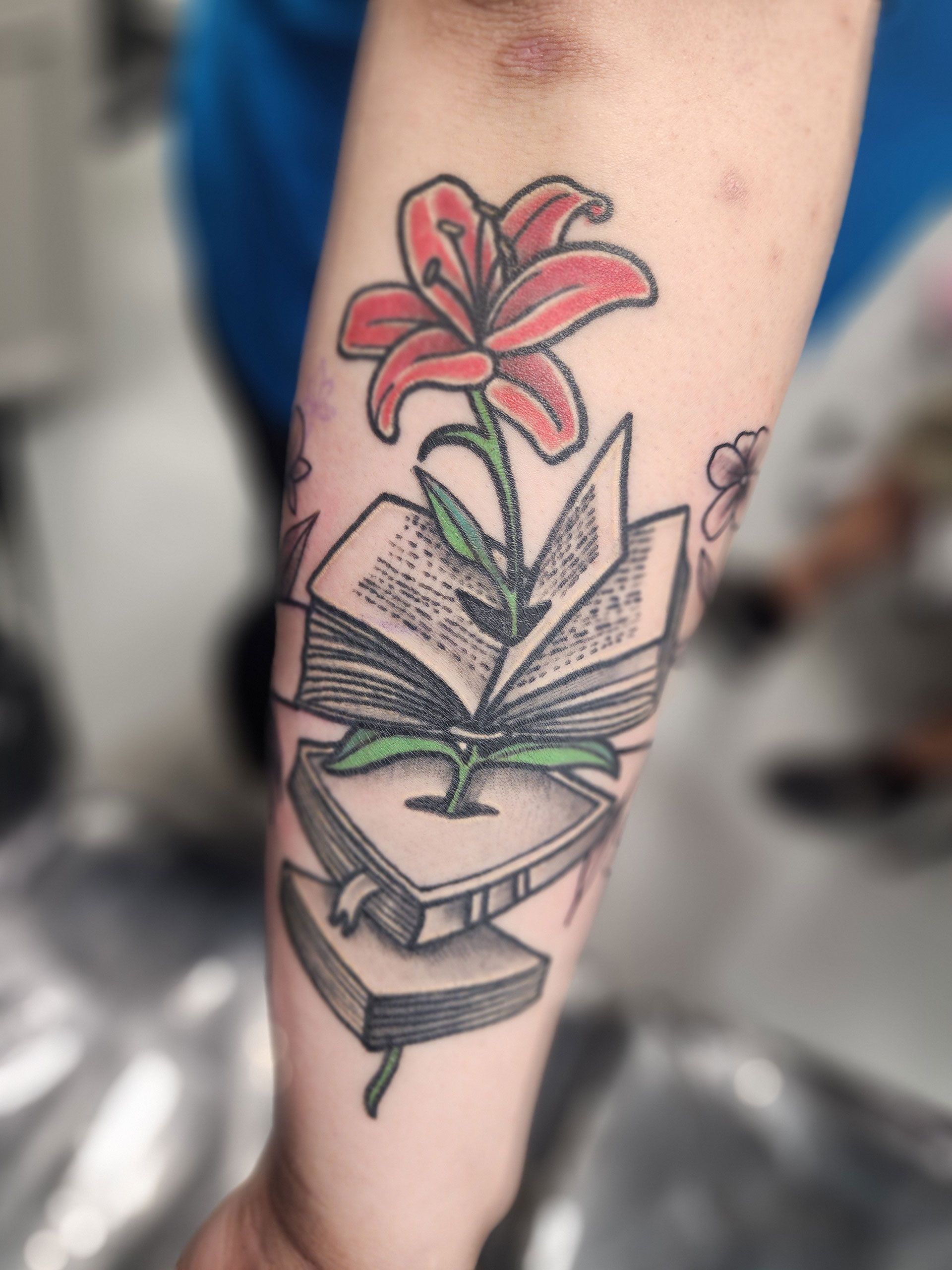 A tattoo of an open book with a flower growing out of it