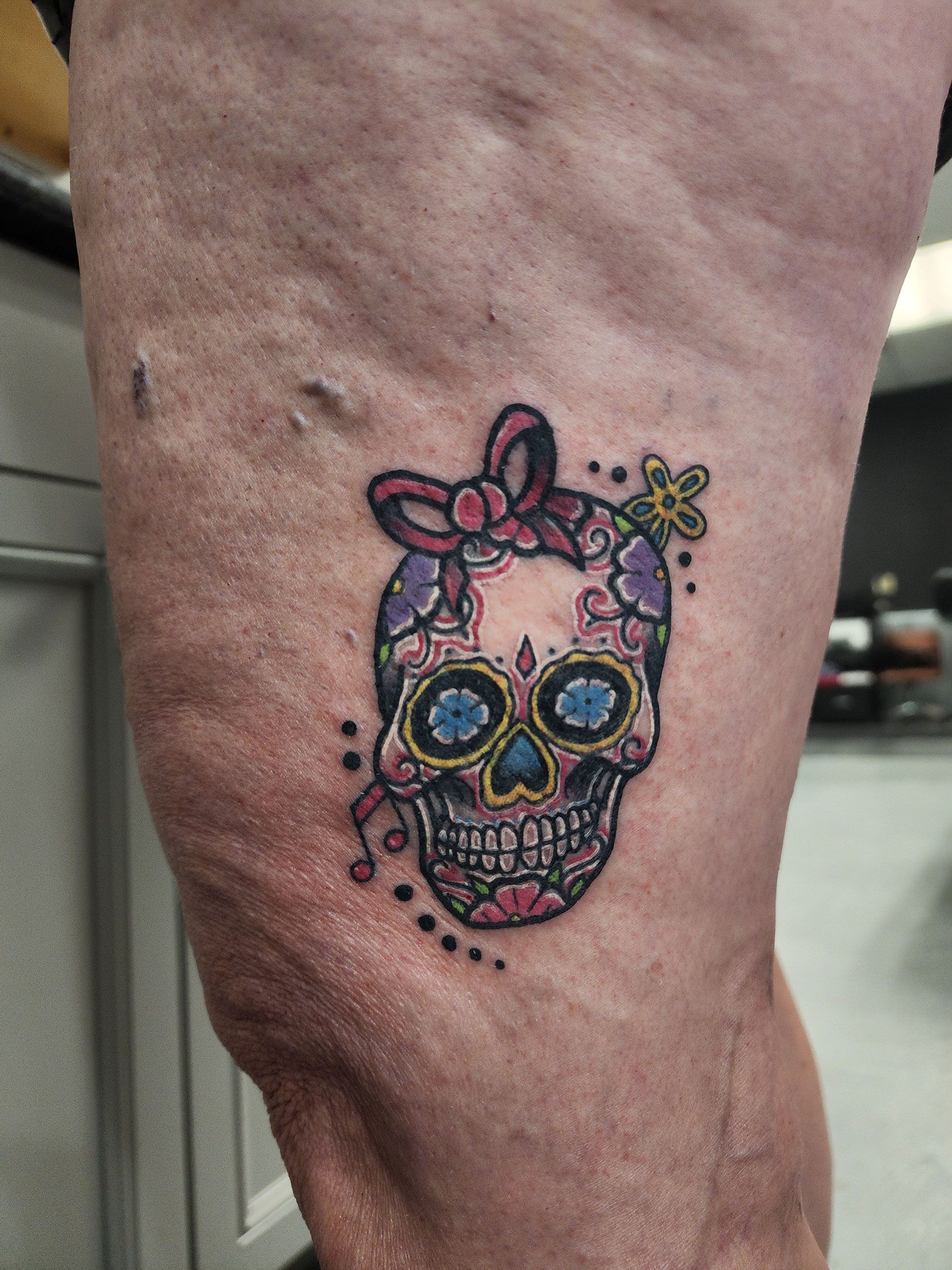 A woman has a sugar skull tattoo on her leg.