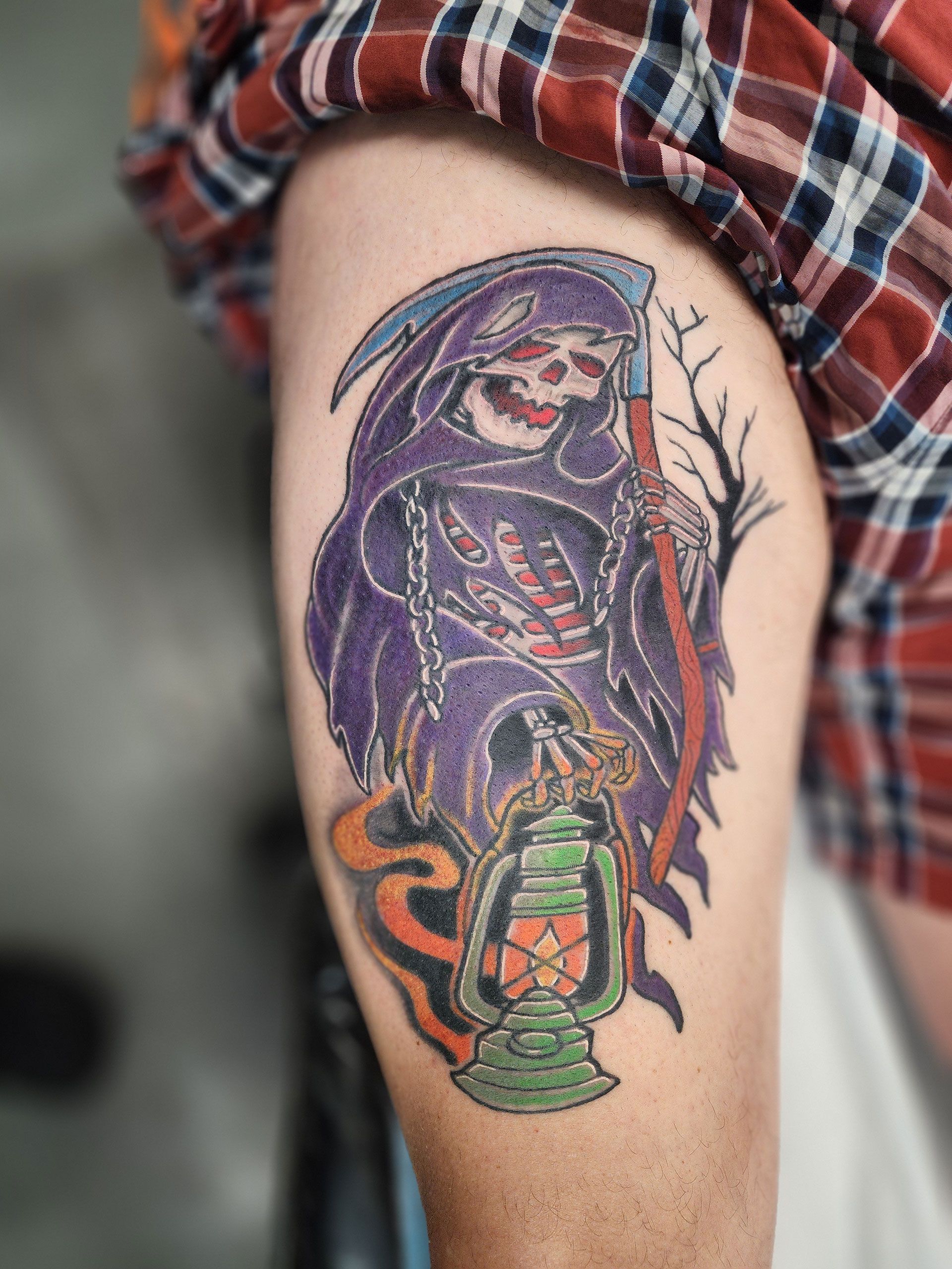 A tattoo of a grim reaper holding a lantern on a person's arm