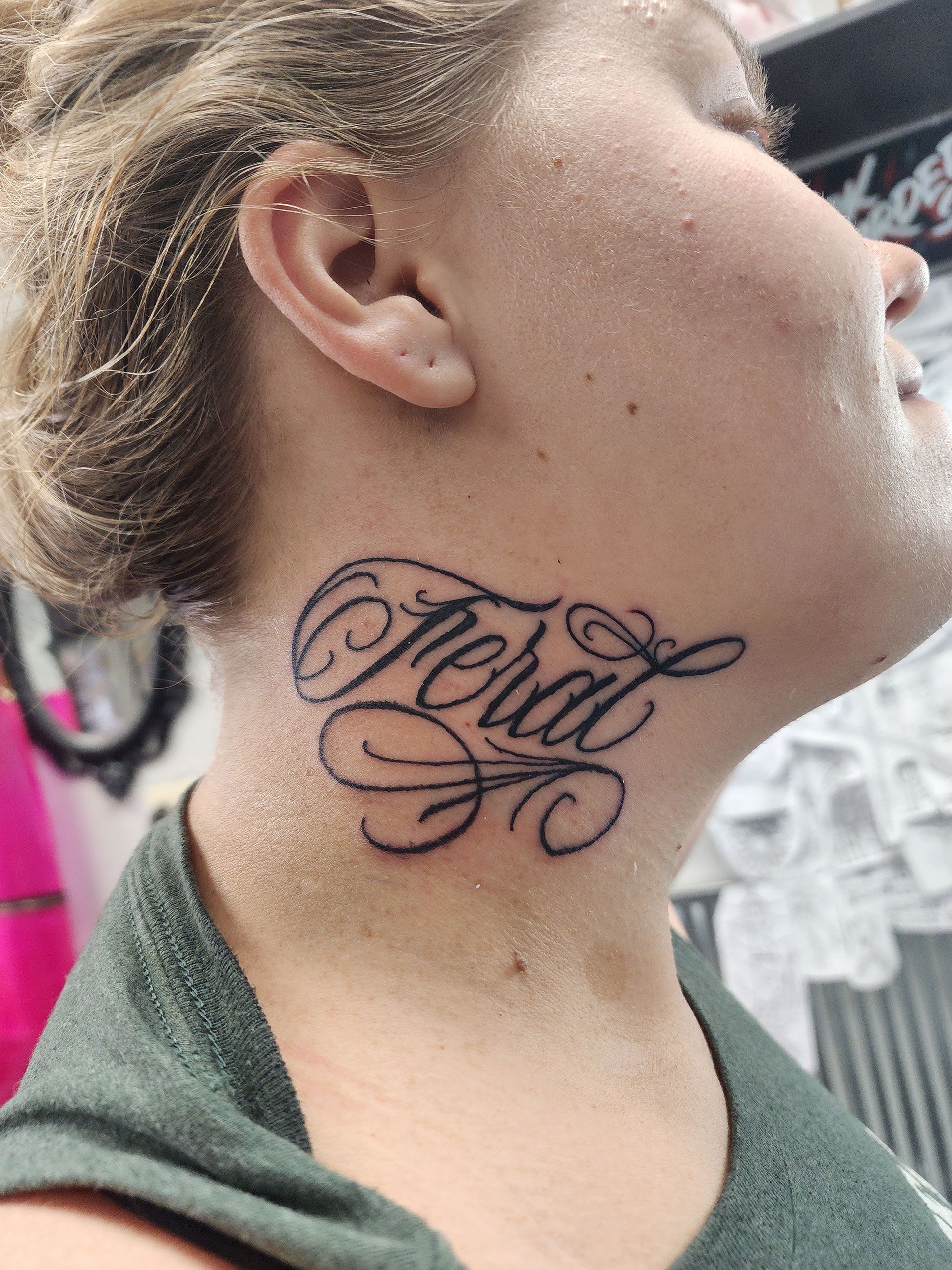 A woman has a tattoo on her neck that says feral