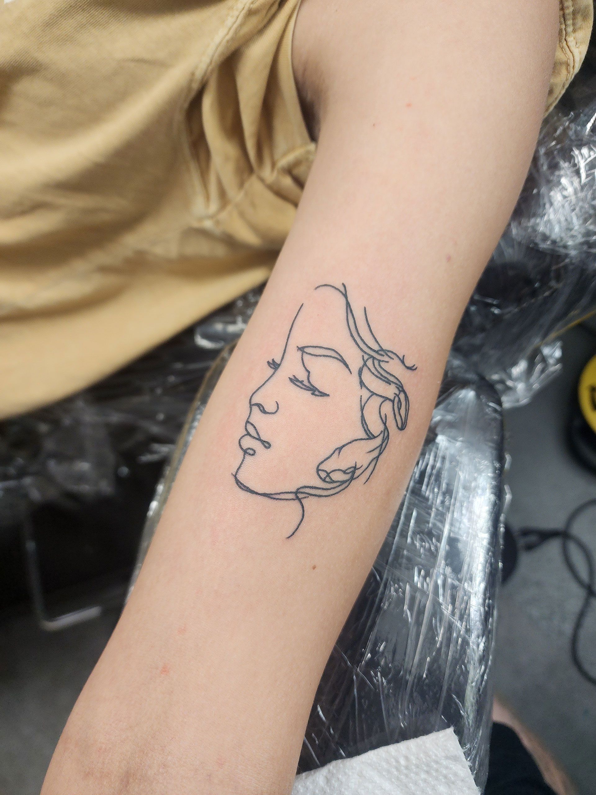 A person has a tattoo of a woman's face on their arm
