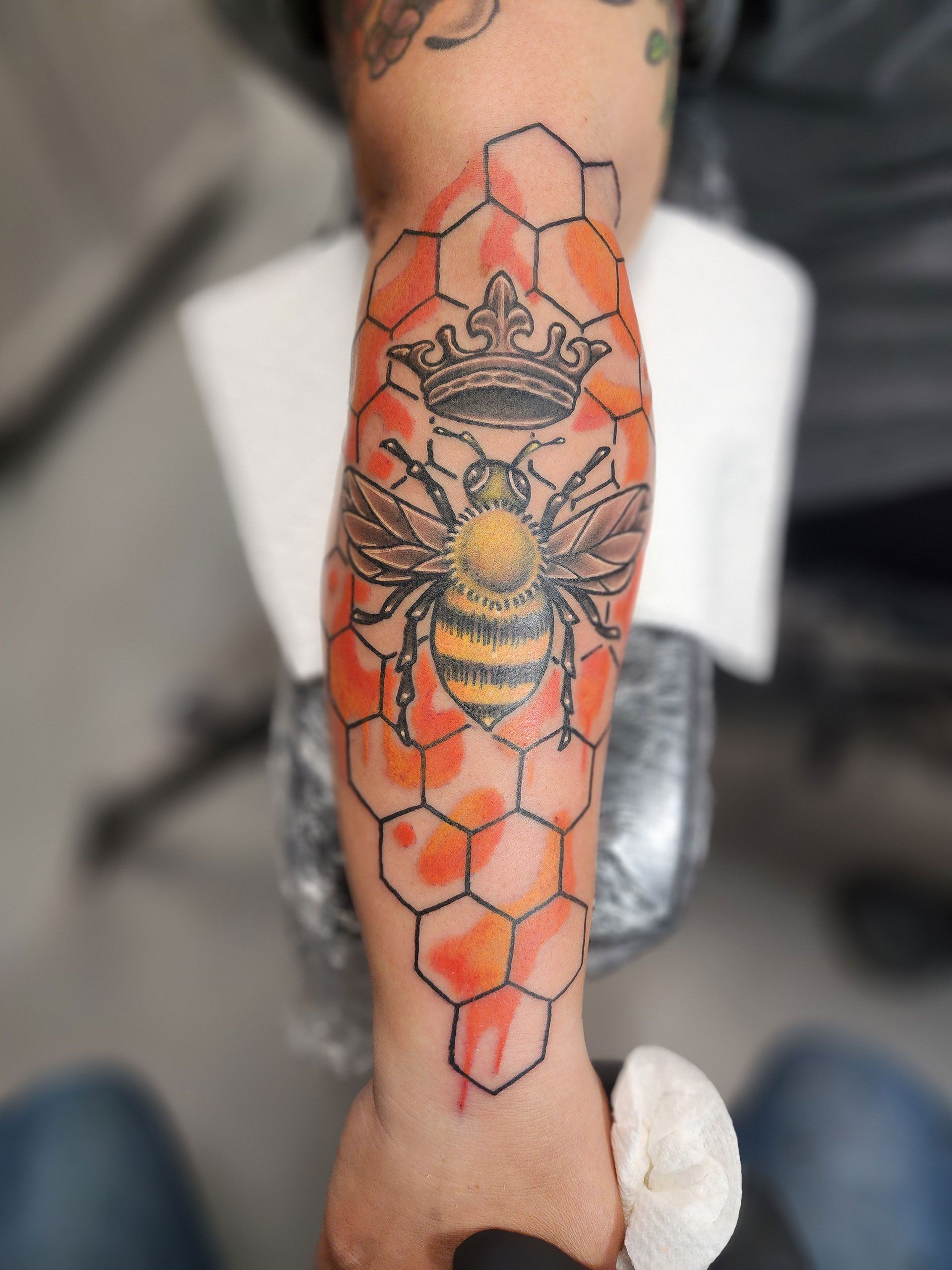 A person has a tattoo of a bee on their arm