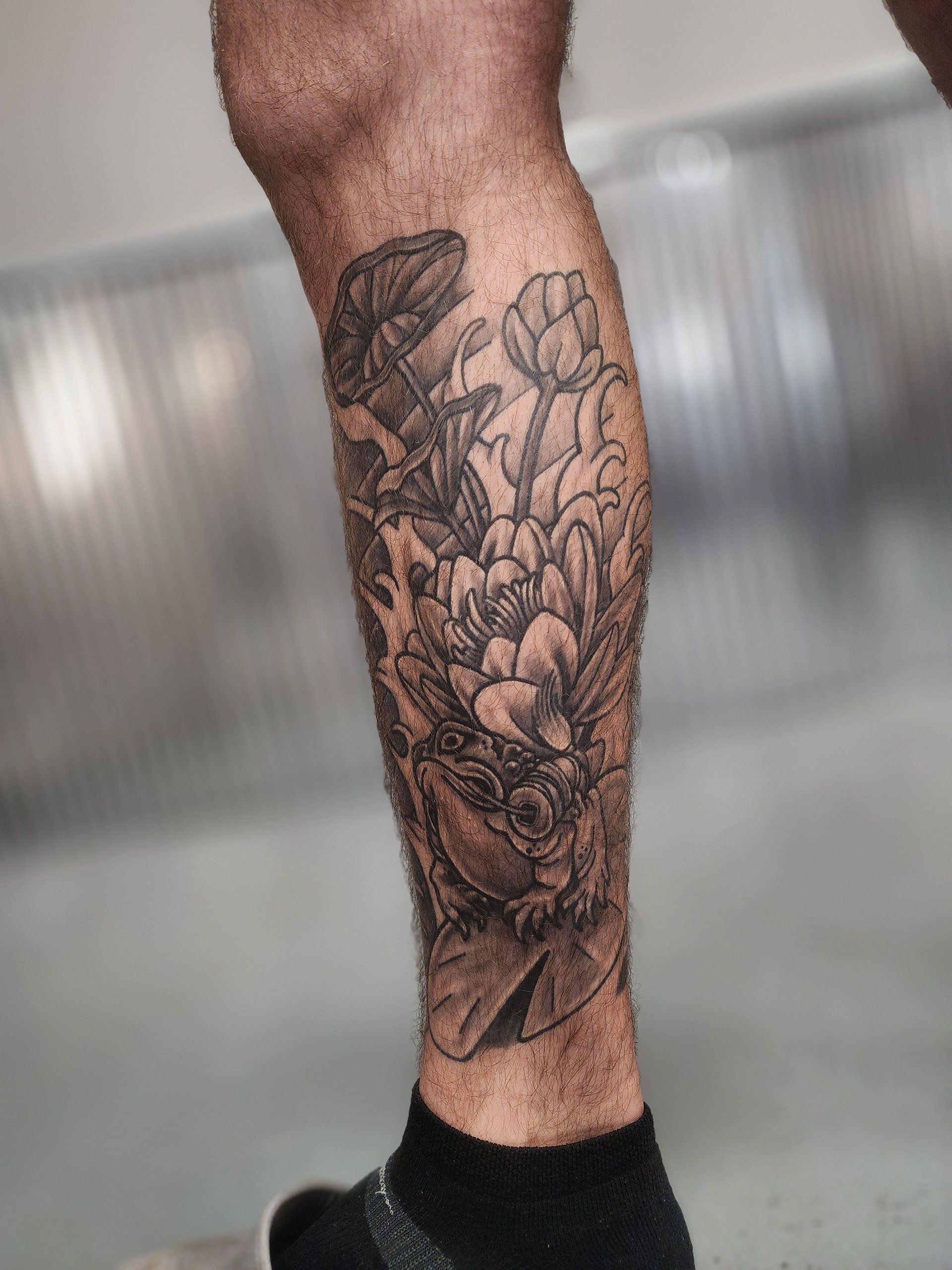 A man has a tattoo of a flower on his leg