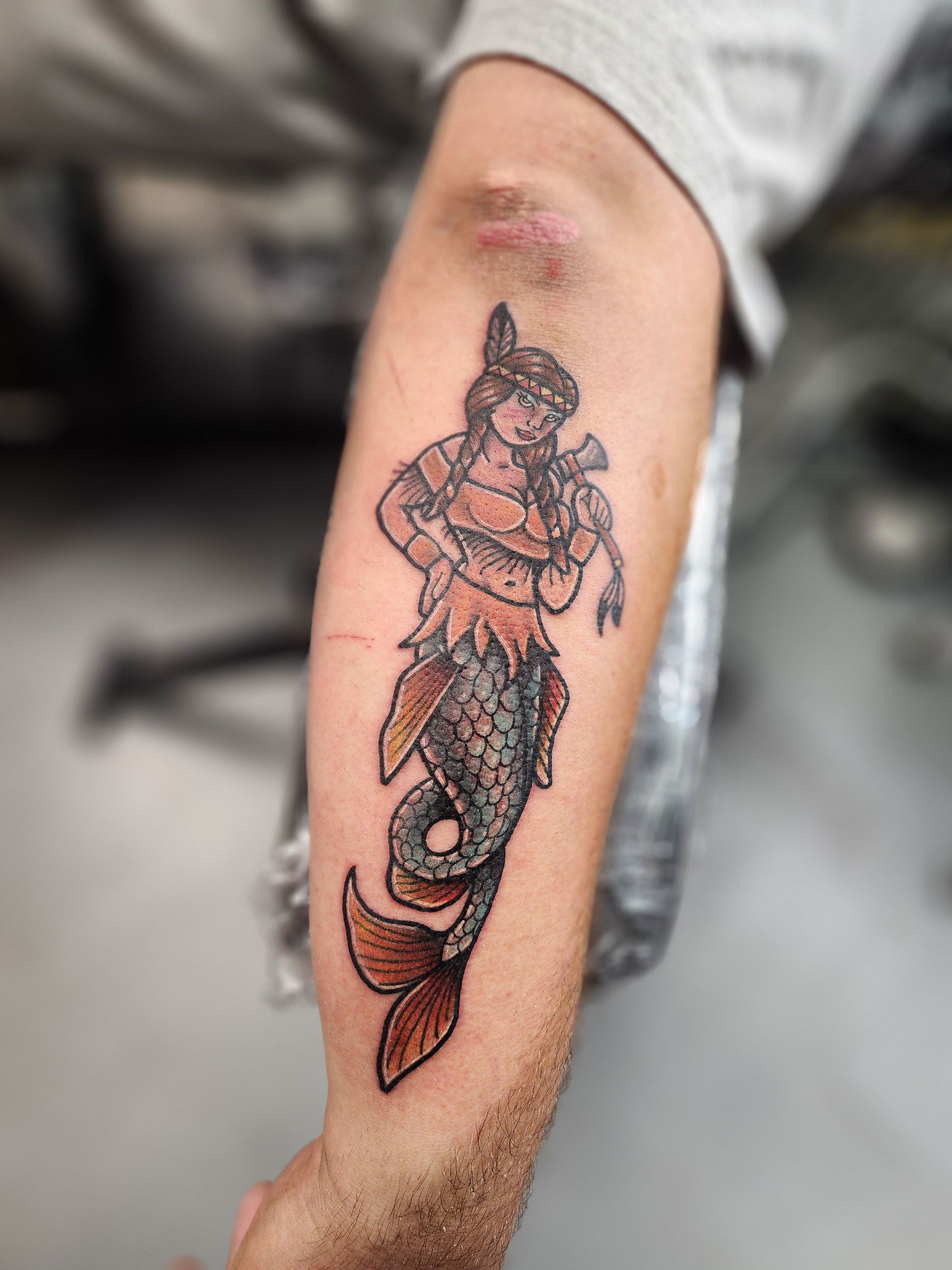 A man has a tattoo of a mermaid on his arm