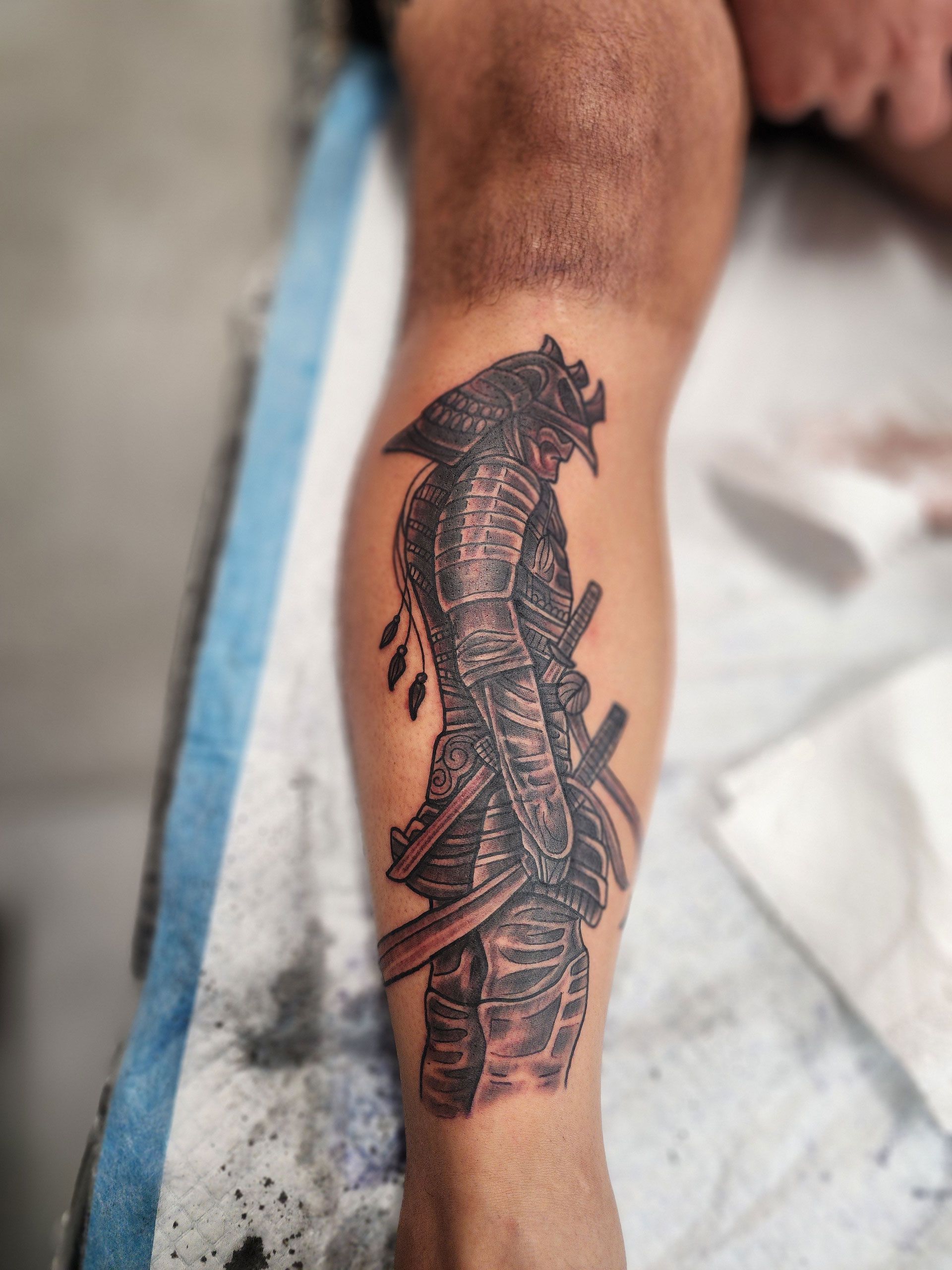 A man has a tattoo of a samurai on his leg