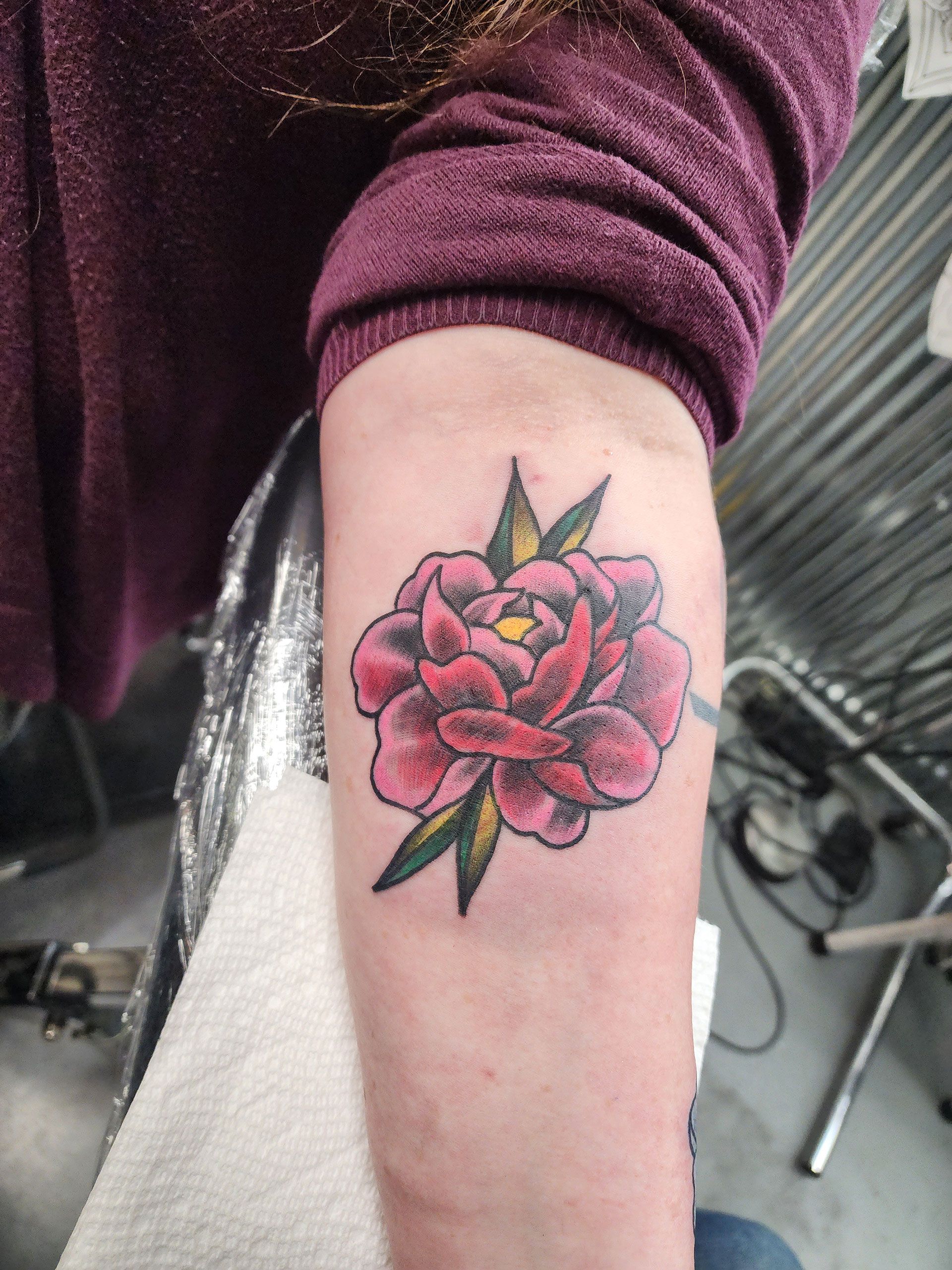A woman has a tattoo of a pink flower on her arm
