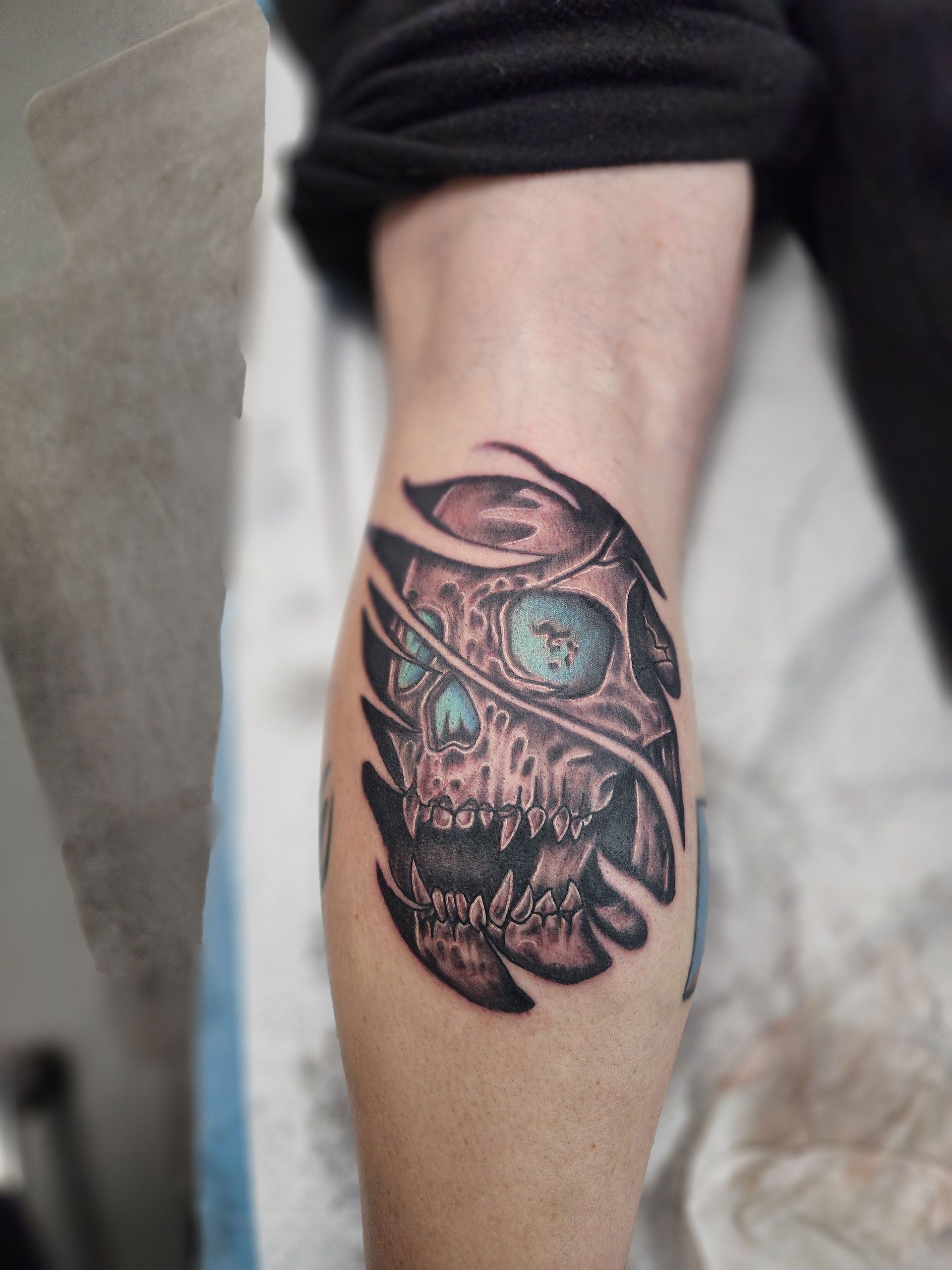 A person has a tattoo of a skull on their leg.