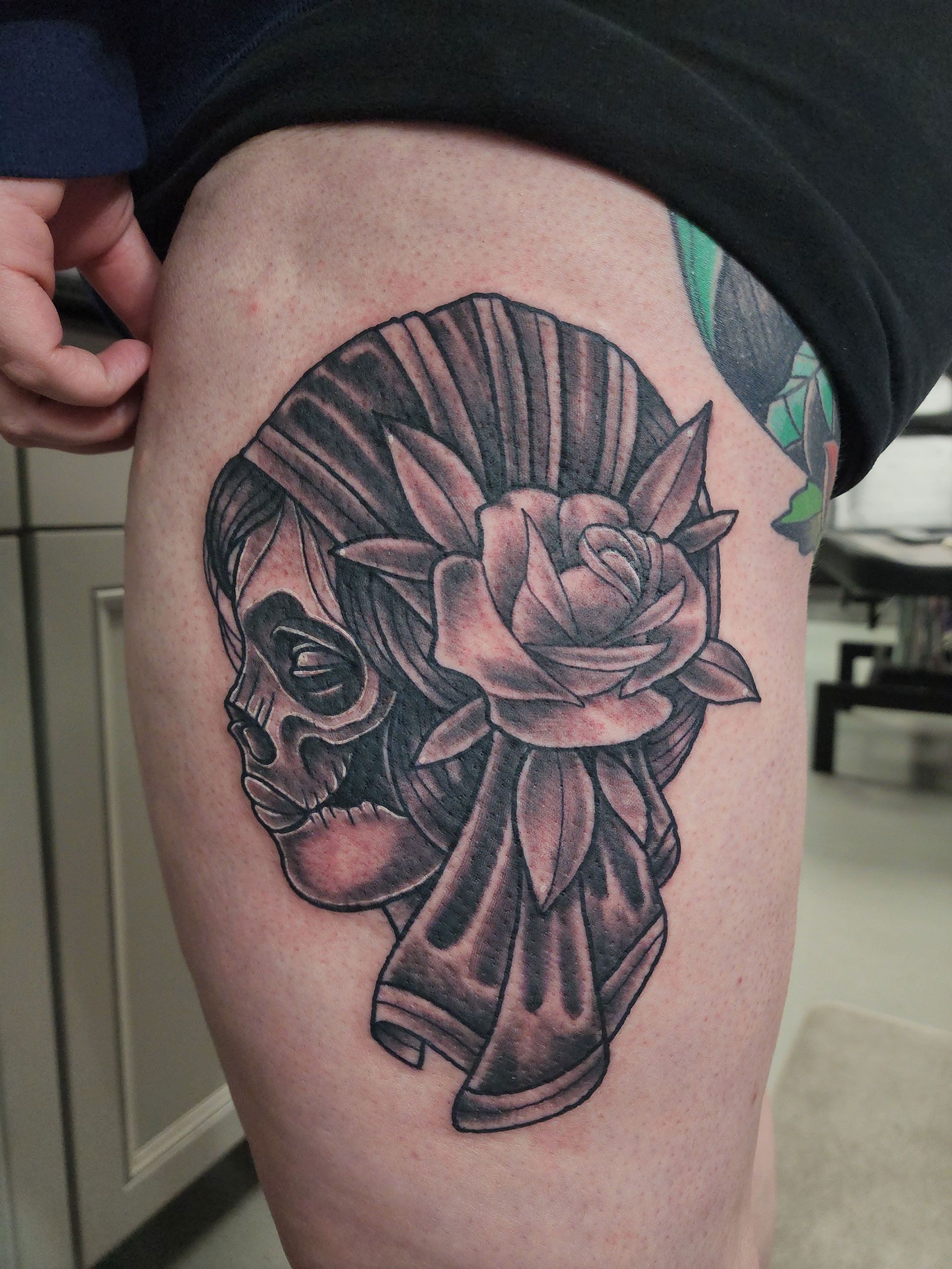 A person has a tattoo of a skull and a rose on their leg