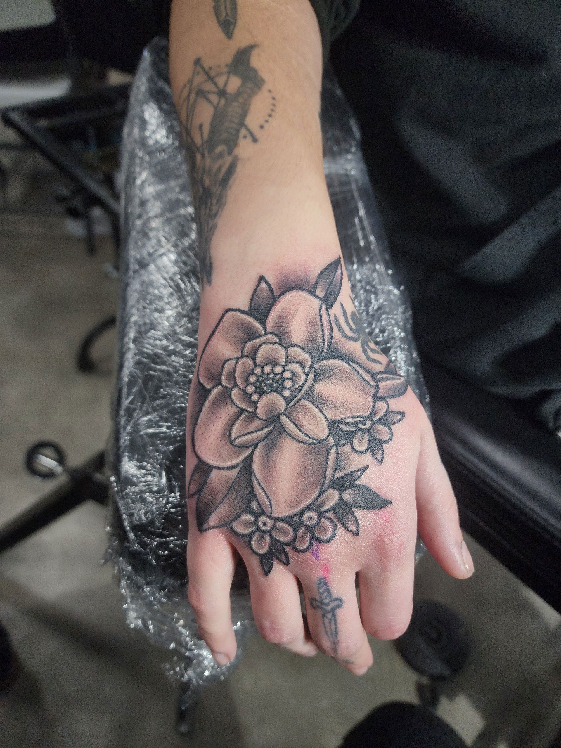 A person has a tattoo of a flower on their hand