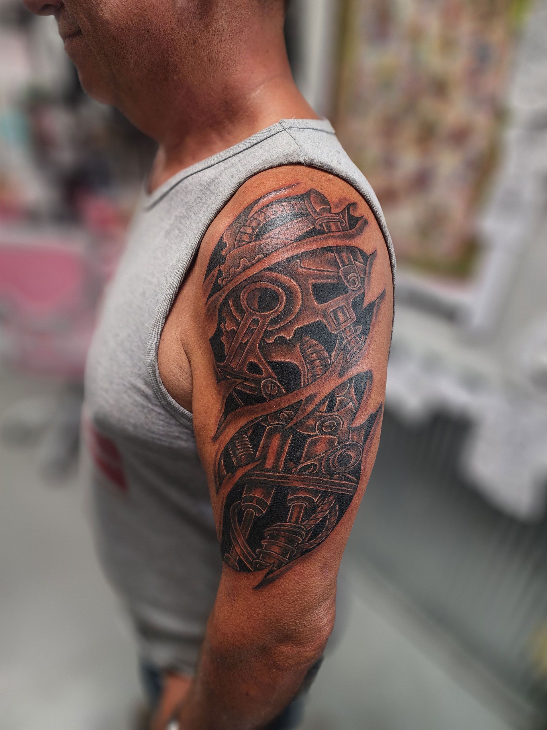 A man with a tattoo on his arm is wearing a gray tank top