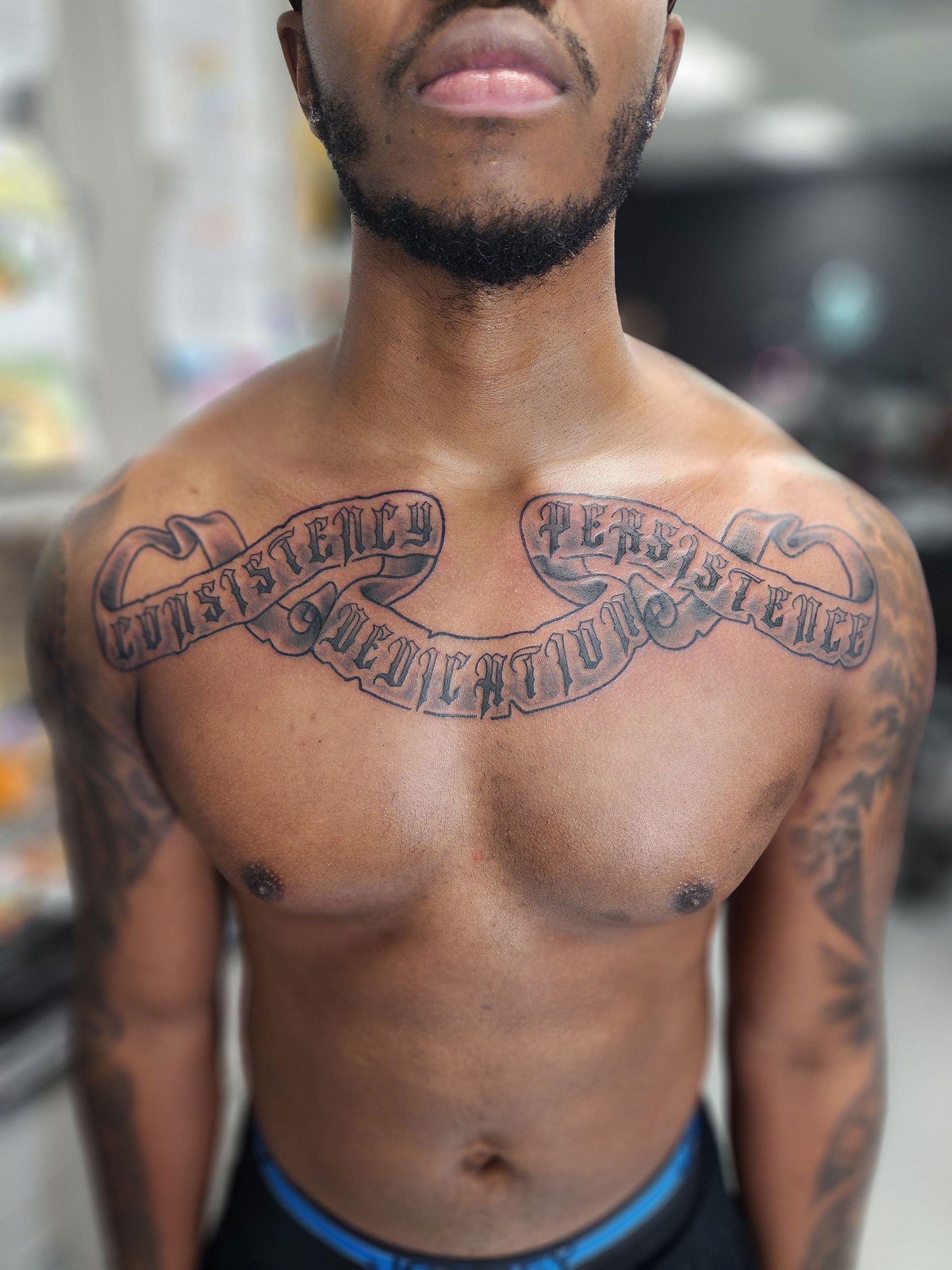 A shirtless man with a tattoo on his chest