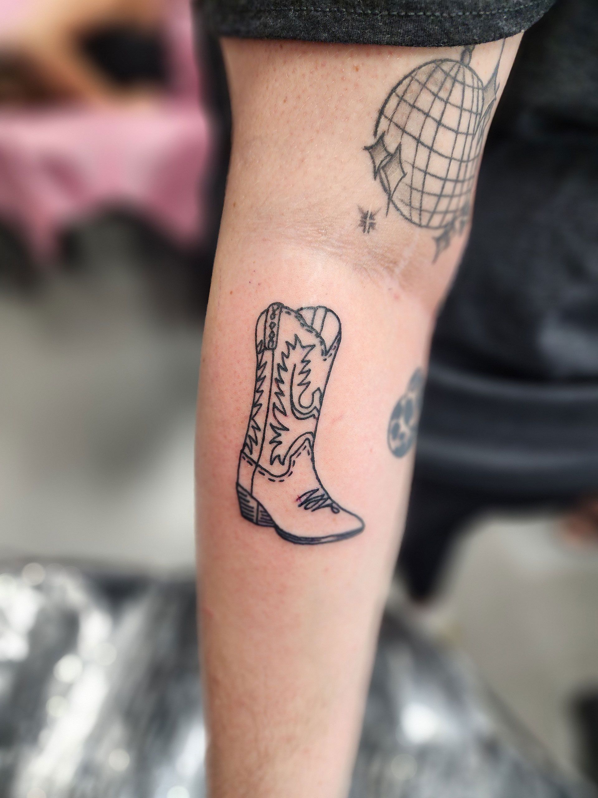 A person has a tattoo of a cowboy boot on their leg