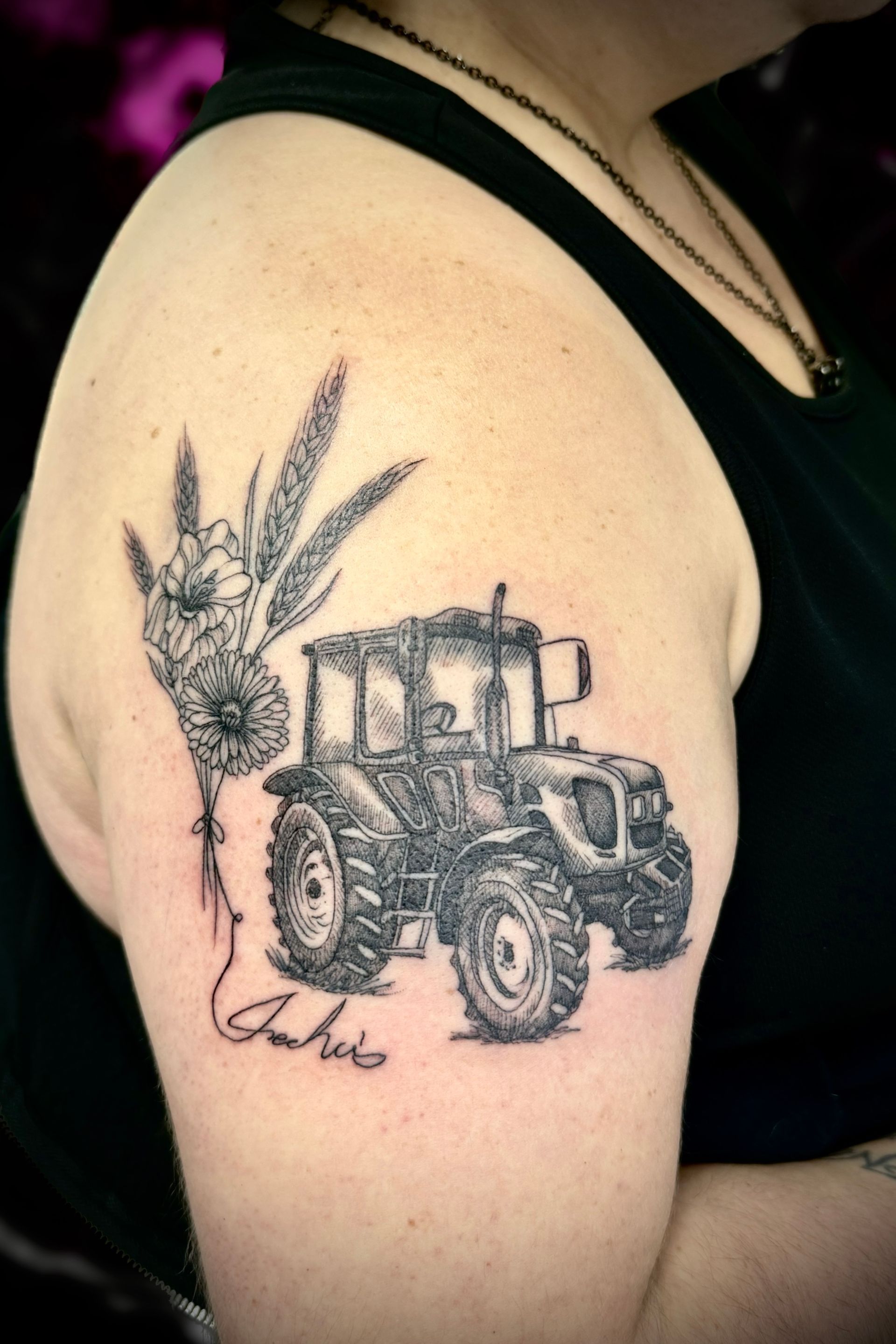A woman has a tattoo of a tractor on her arm