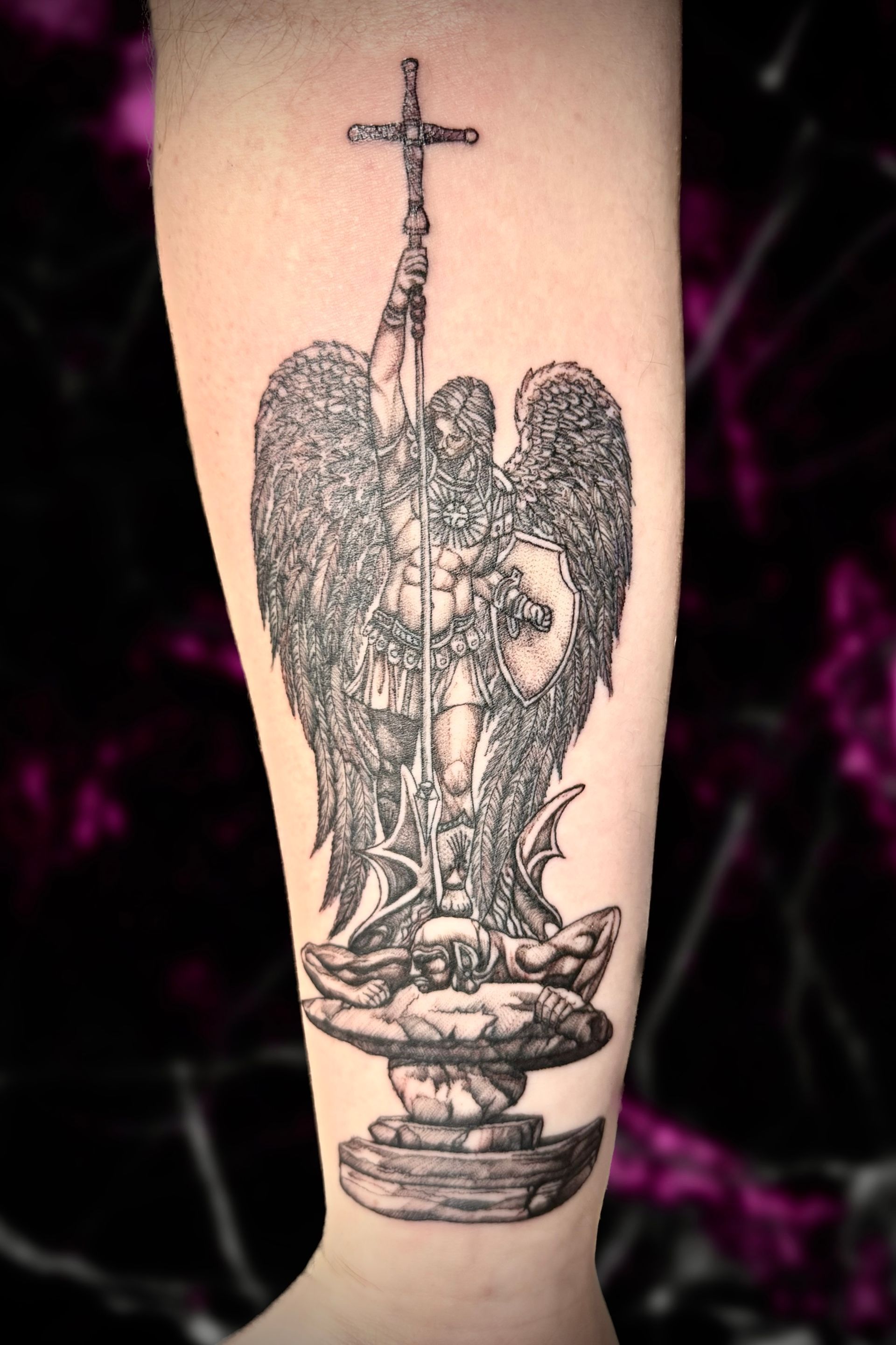 A tattoo of a man with wings holding a cross