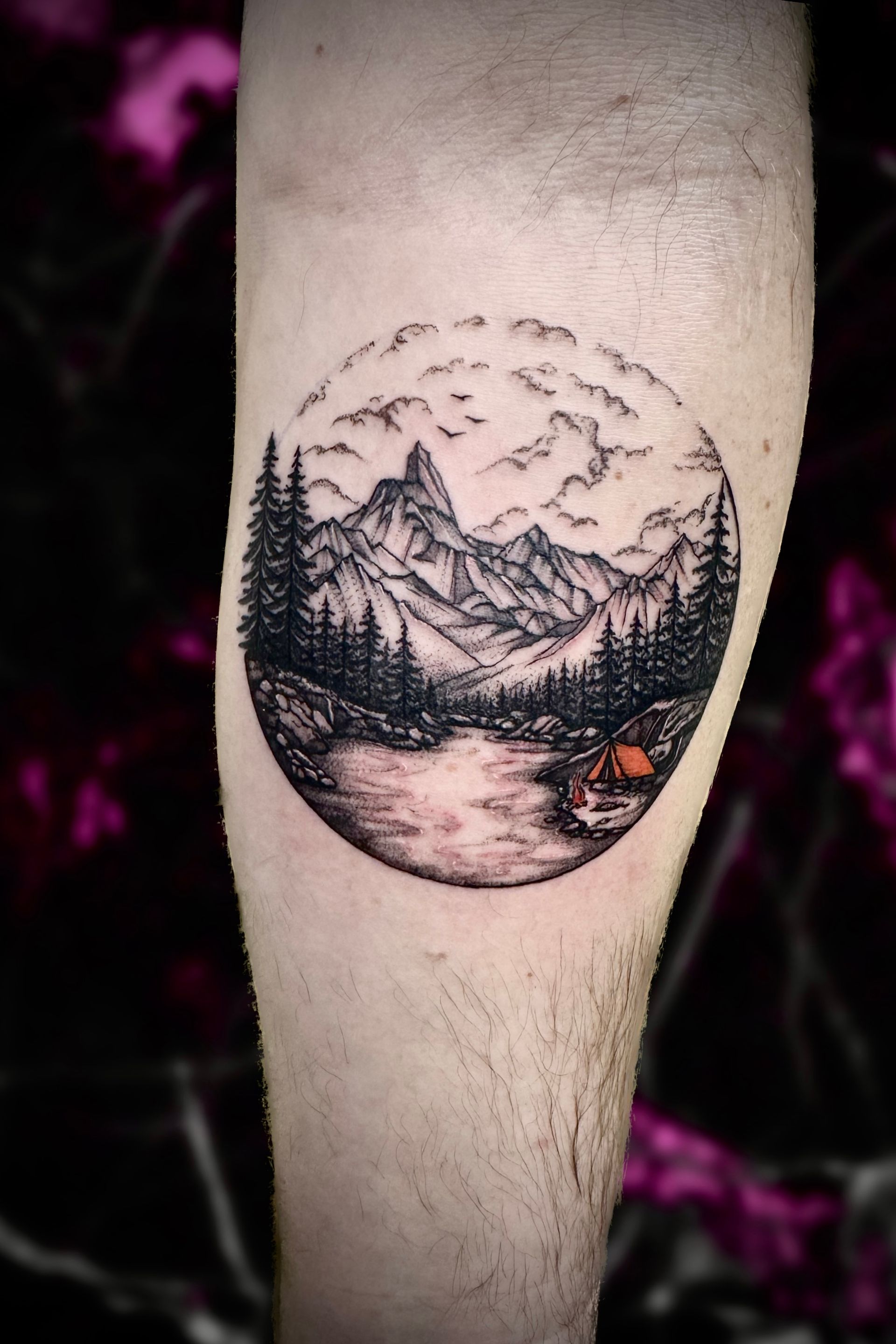 A person has a tattoo of a mountain landscape on their leg