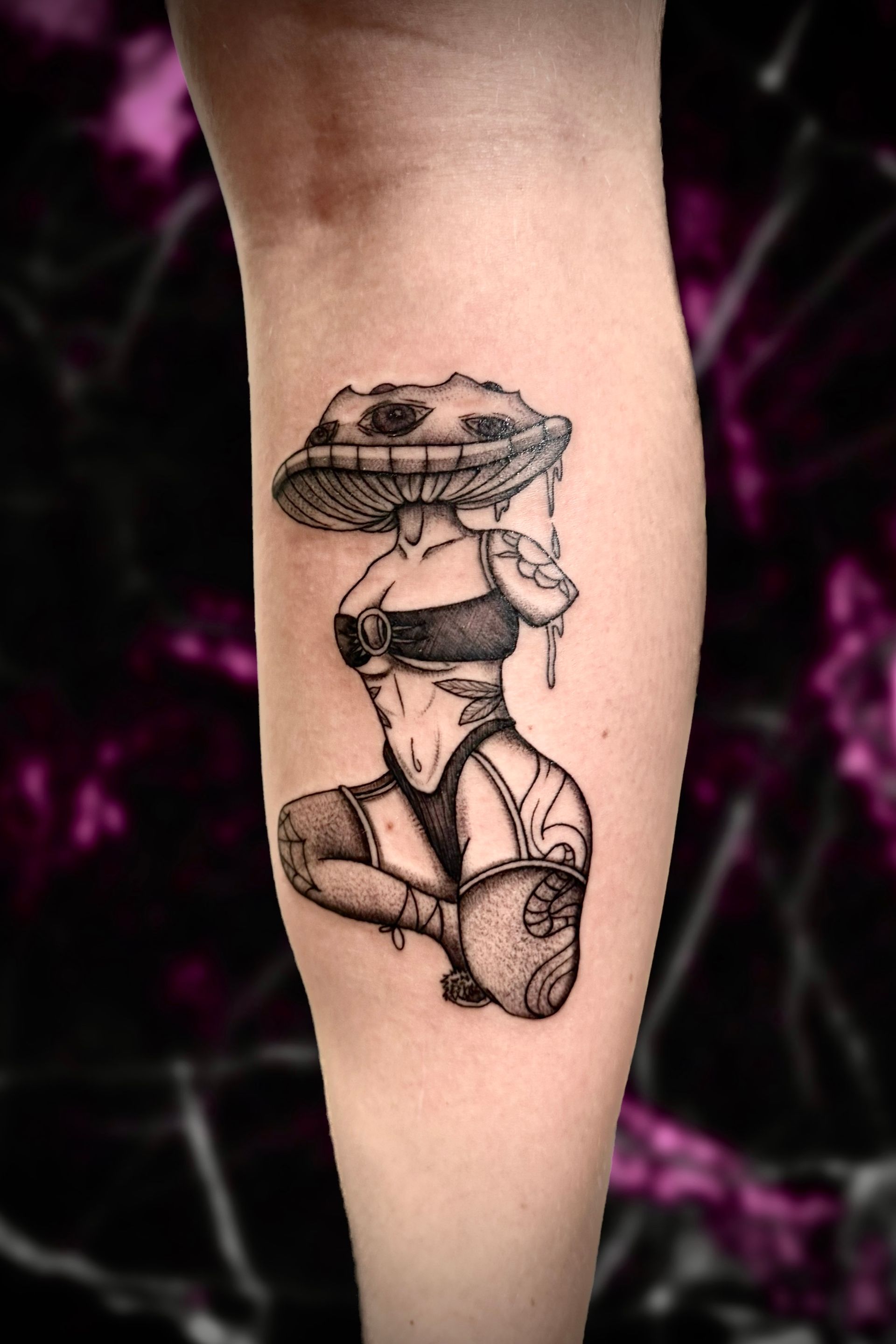 A black and white tattoo of a woman with a mushroom on her head