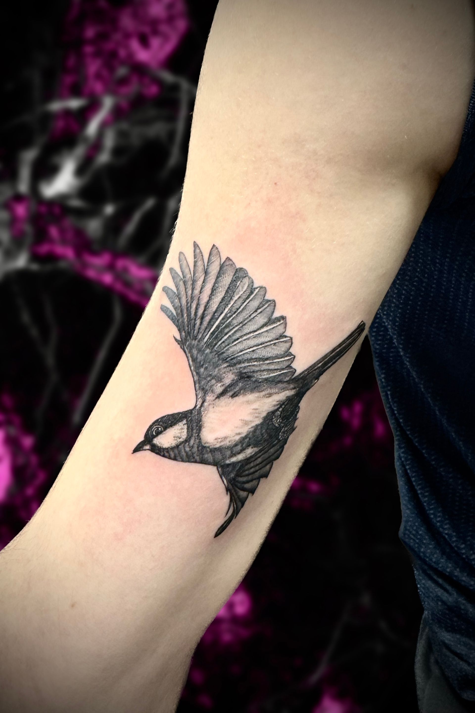 A person has a tattoo of a bird on their arm