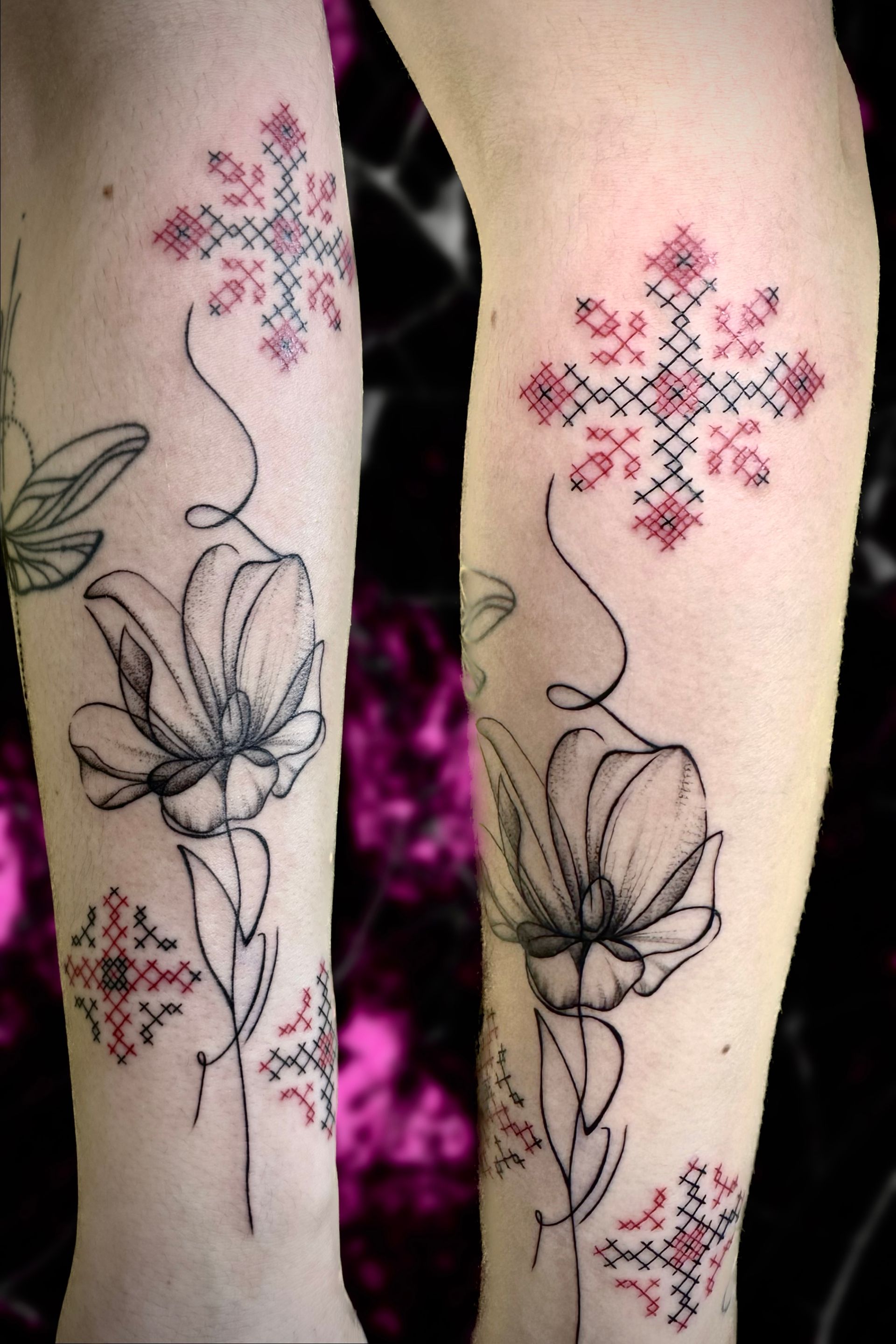 A woman has a tattoo of flowers and a cross on her leg
