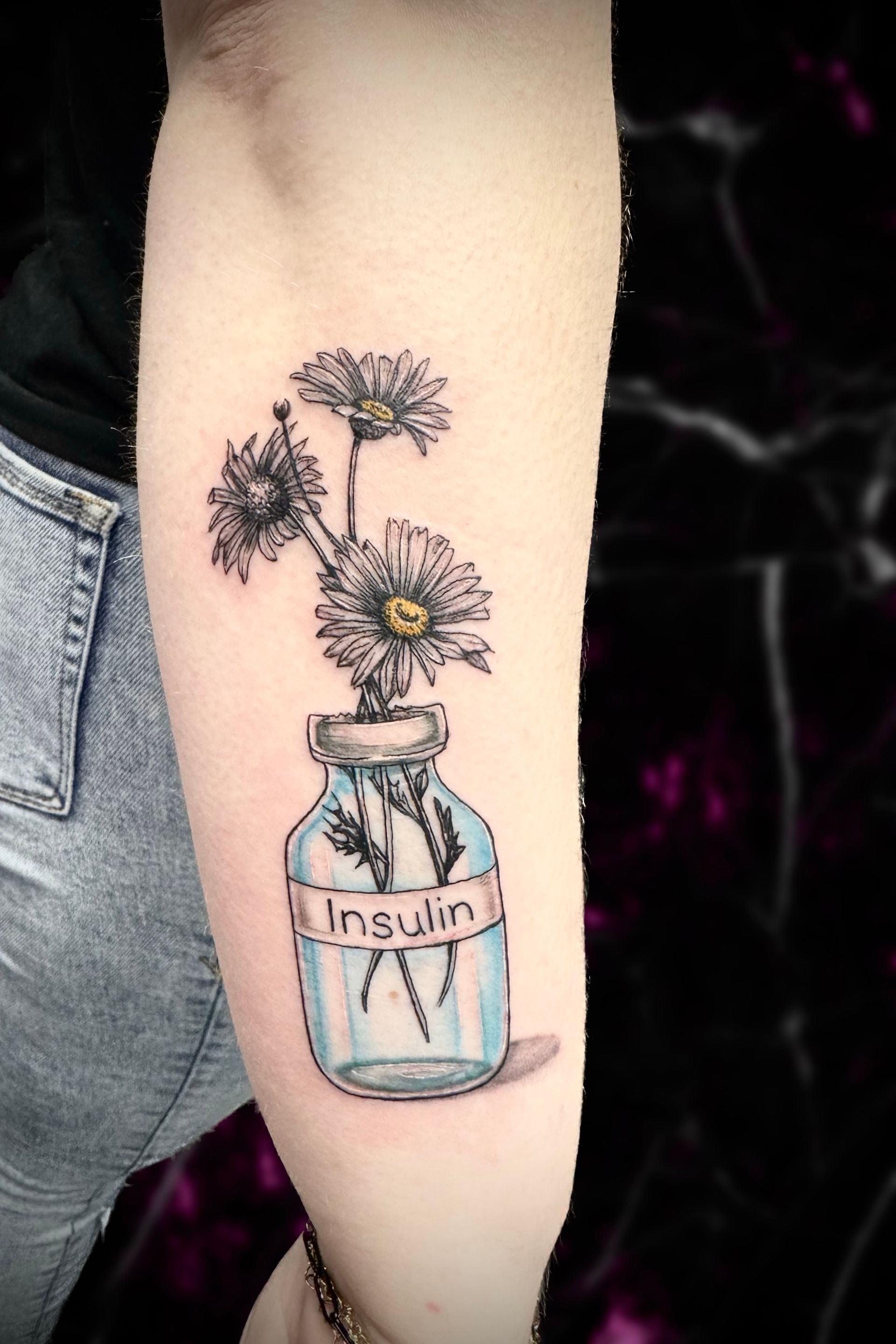 A woman has a tattoo of flowers in a jar that says insulin