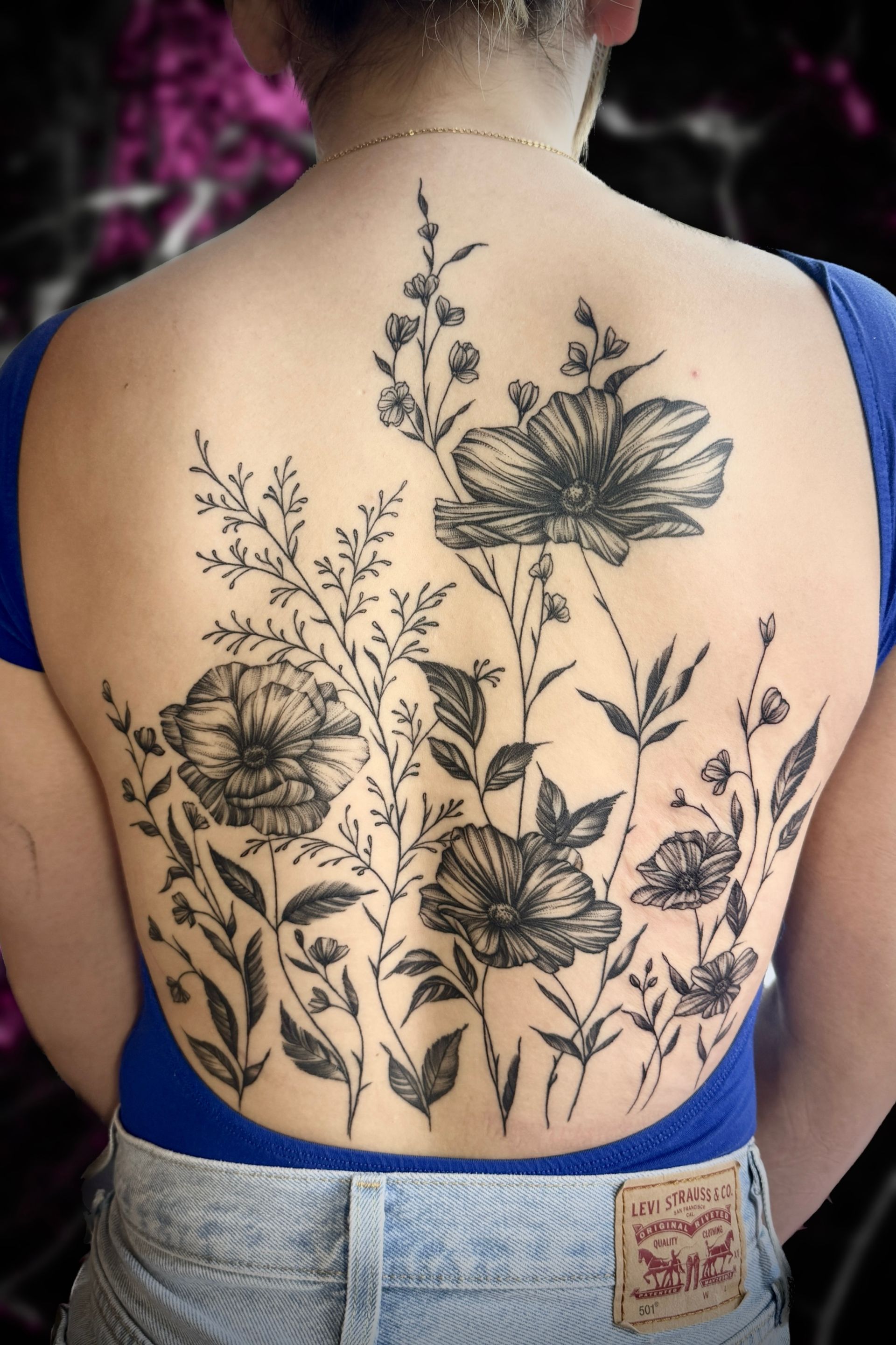 A woman has a tattoo of flowers on her back