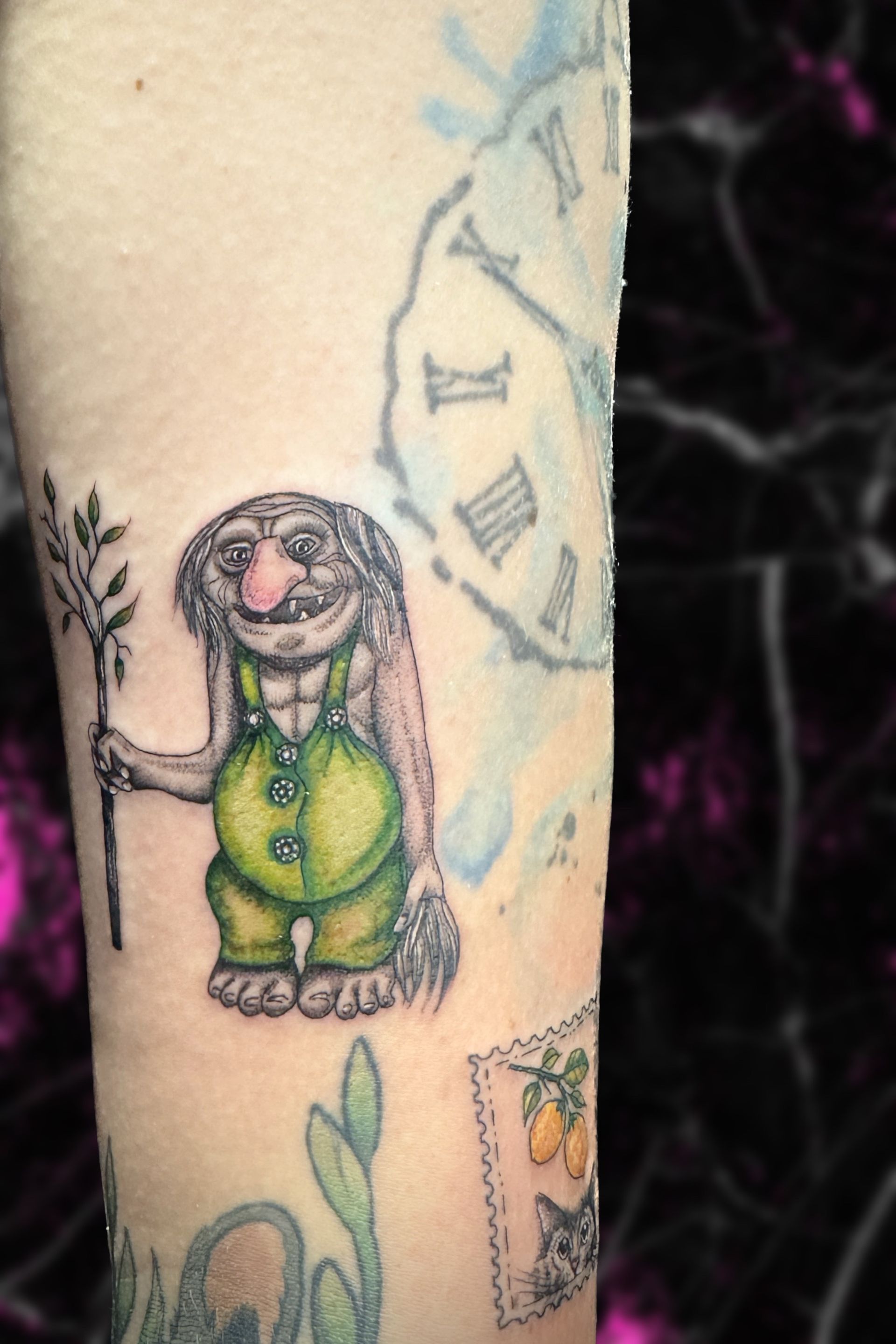 A person has a tattoo of a troll on their arm