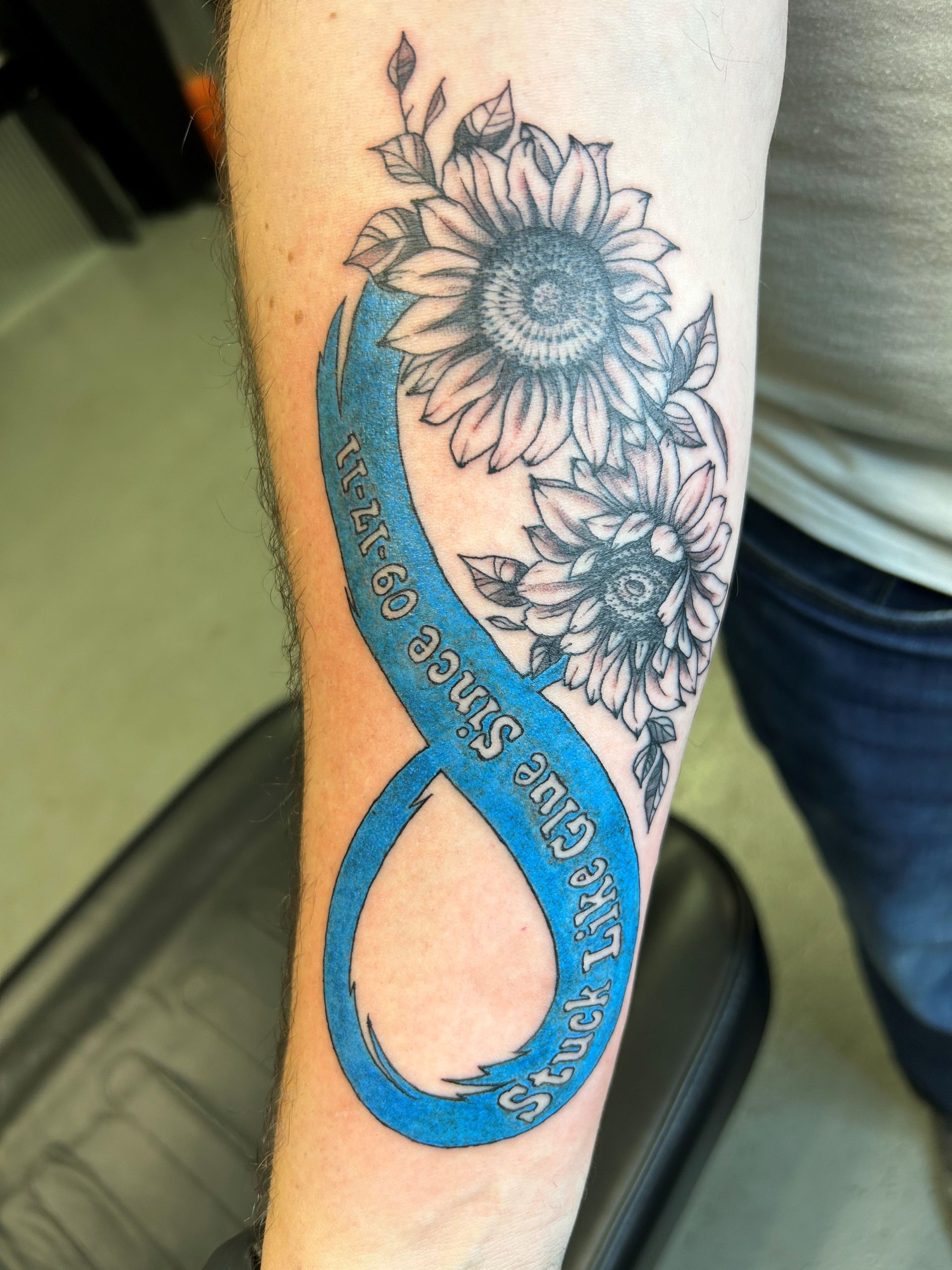 A person has a tattoo of an infinity symbol with sunflowers
