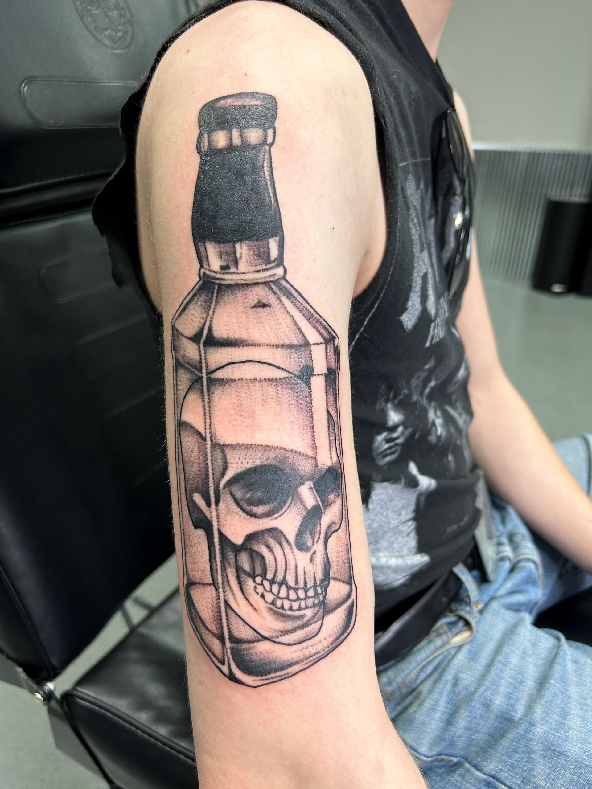 A man has a tattoo of a skull in a bottle on his arm