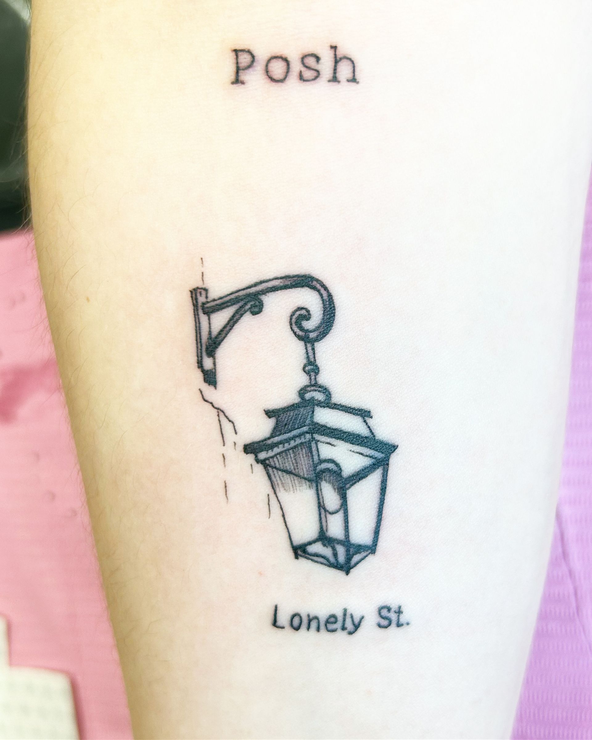 A tattoo on a person 's arm that says posh lonely st.