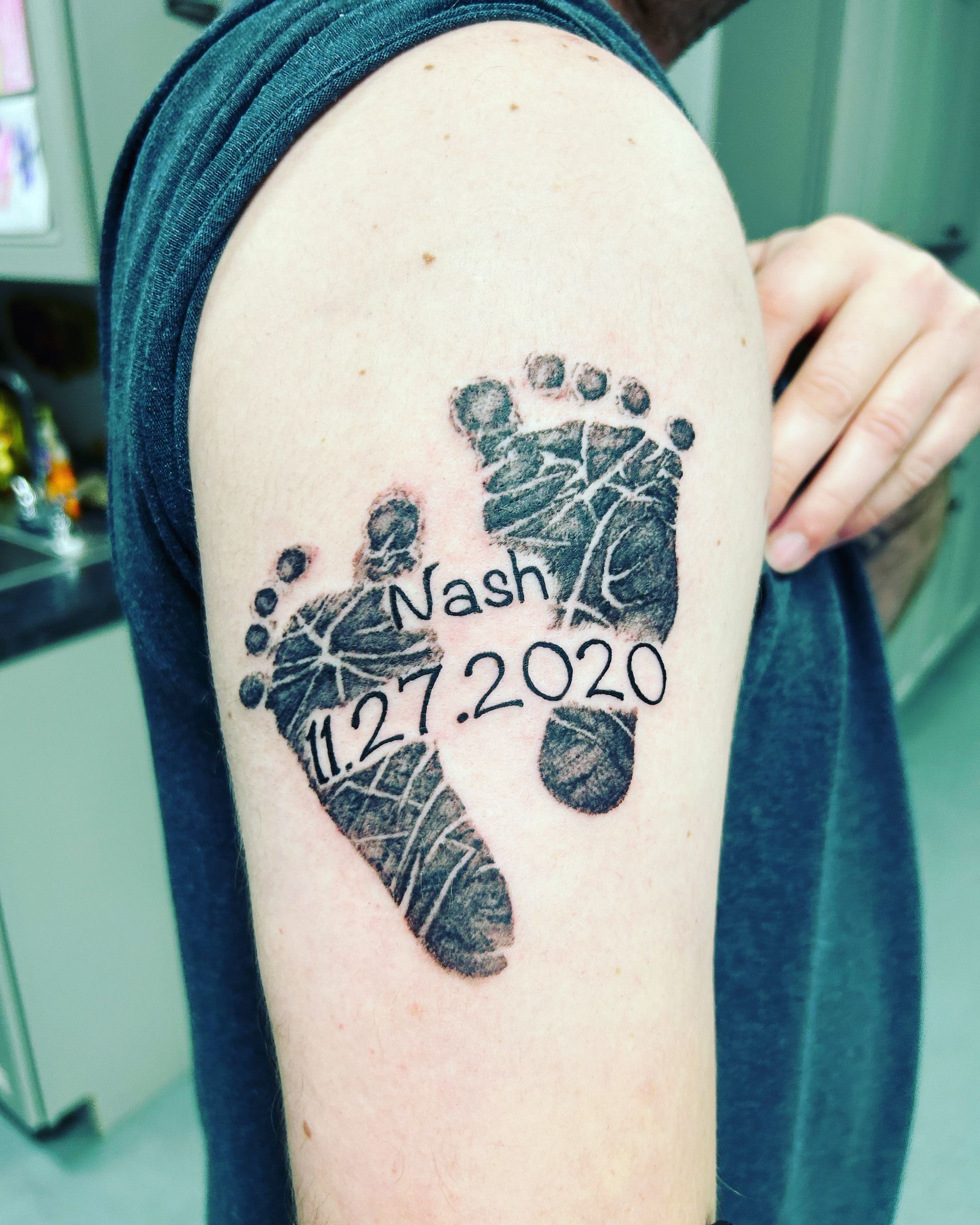 A man has a tattoo of a baby 's footprint on his arm