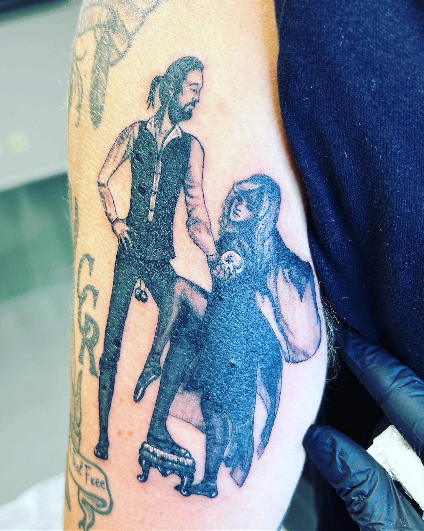 A tattoo of a man and a woman on a person 's arm