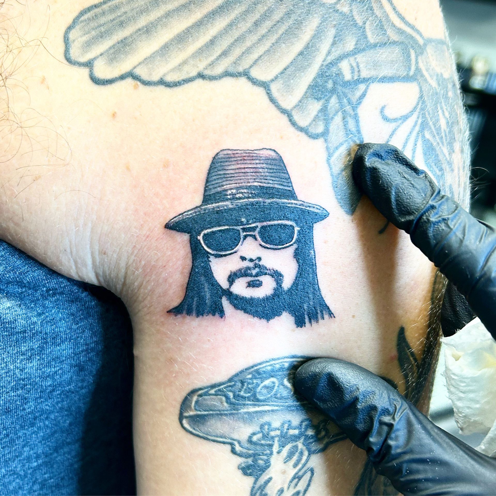A tattoo of a man wearing a hat and sunglasses
