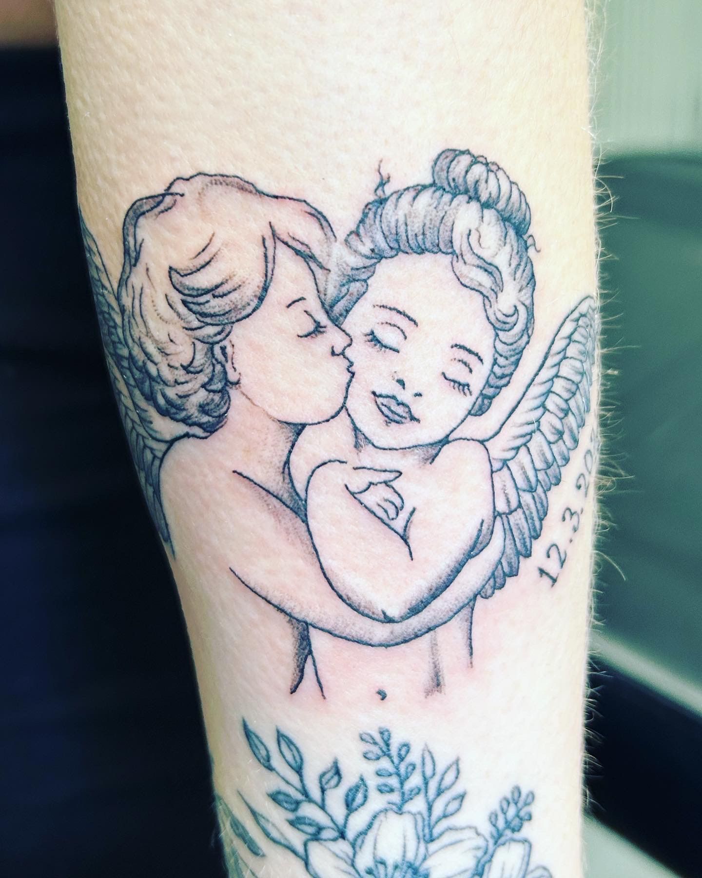 A woman has a tattoo of two angels hugging each other