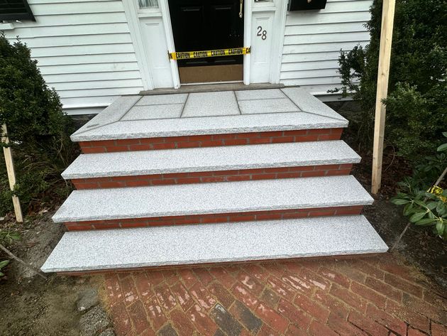 Front steps with white stone treads and red brick risers leading to a house entrance