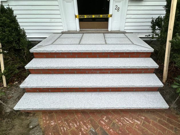 Front steps with white stone treads and red brick risers leading to a house entrance