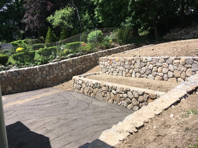 Stone terraced steps and retaining walls beside a paved path in a landscaped park