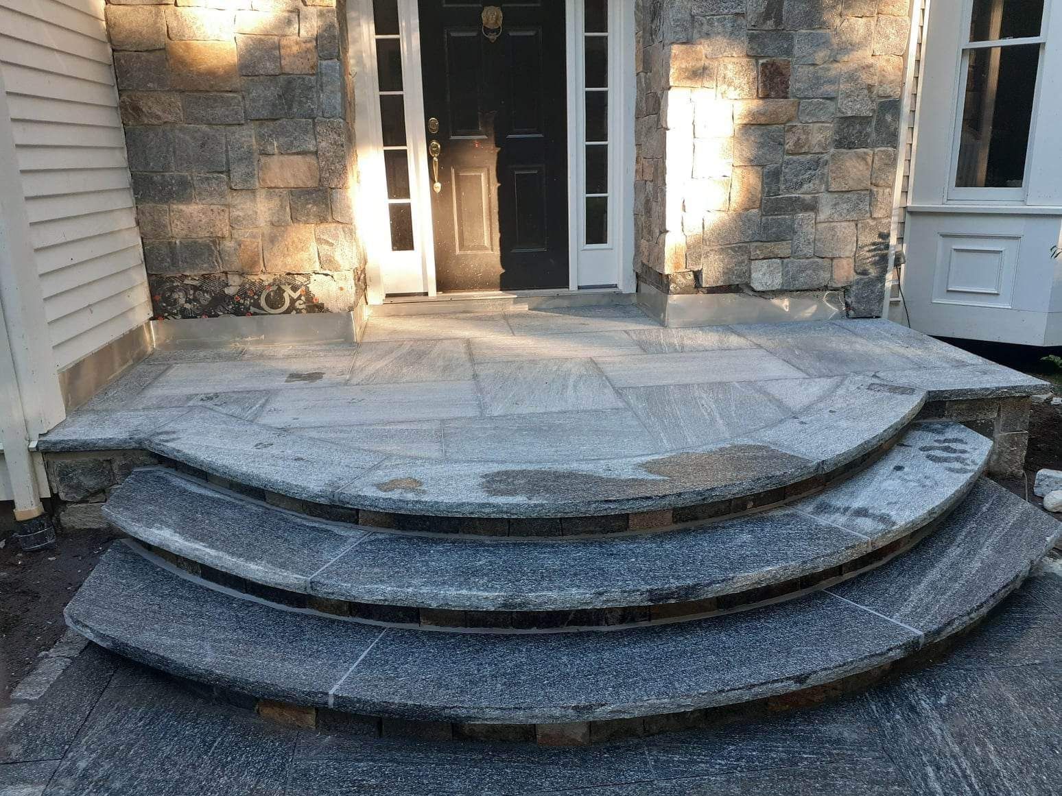 Stone front steps and porch with a circular landing at a house entrance