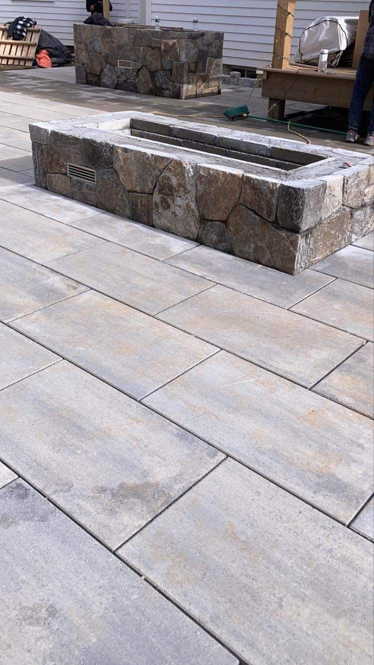 Stone benches on a paved patio with a small fire pit in the background