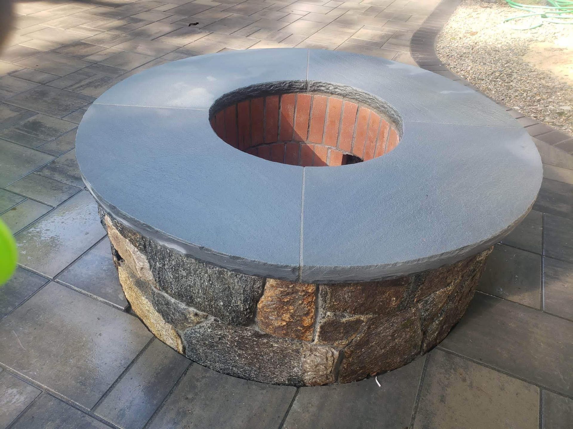 Stone fire pit with a round gray rim and brick-lined center on a paved outdoor area
